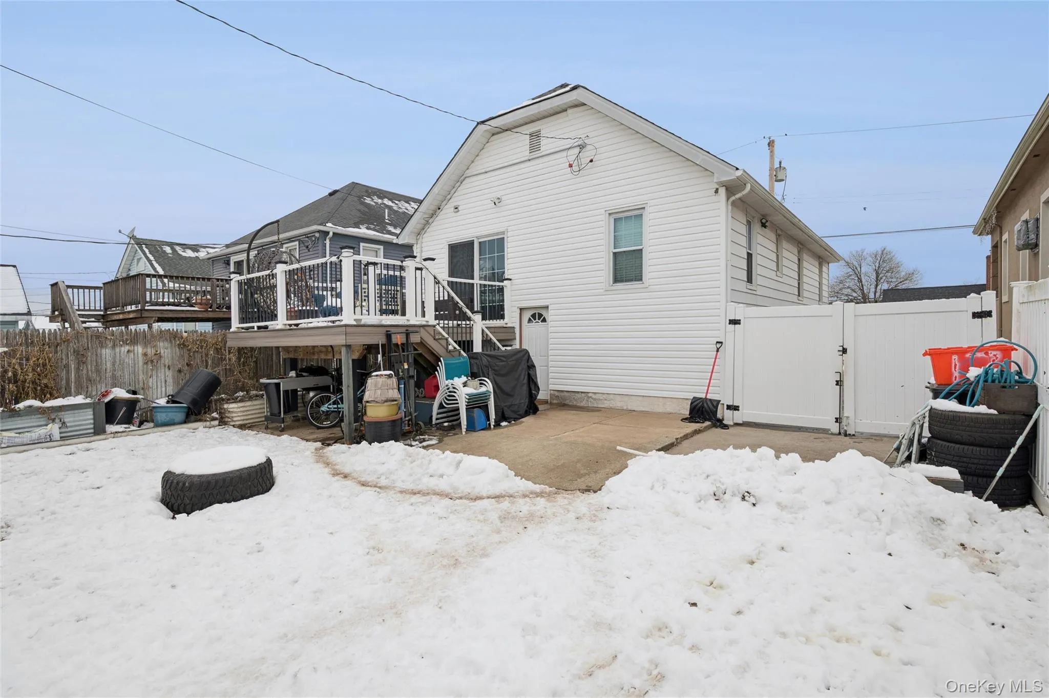 Snow covered rear of property featuring a gate, a wooden deck, a patio area, and stairs Snow covered rear of property featuring a gate, a wooden deck, a patio area, and stairs