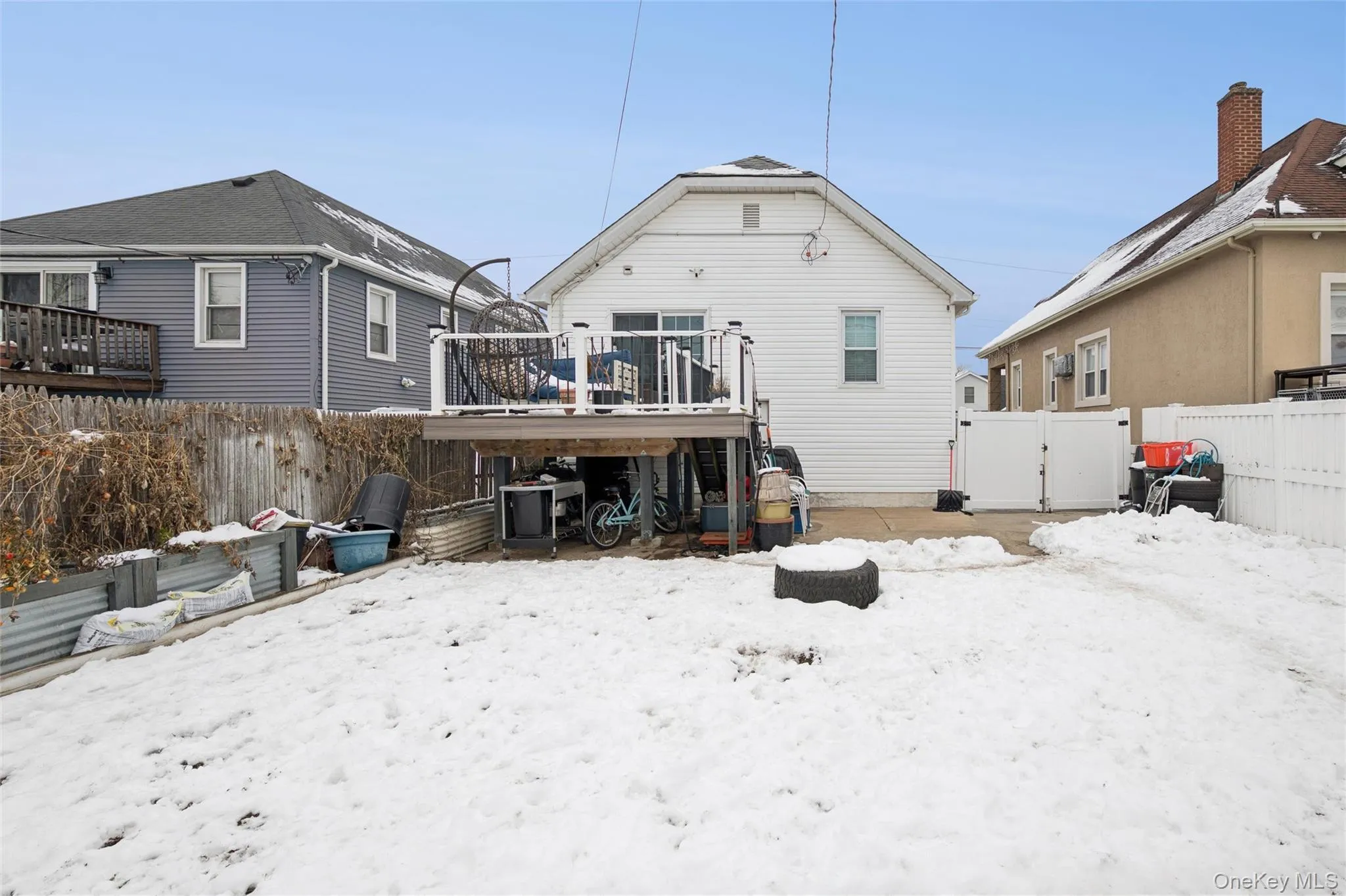 Snow covered house with a fenced backyard, a gate, a deck, and a patio Snow covered house with a fenced backyard, a gate, a deck, and a patio