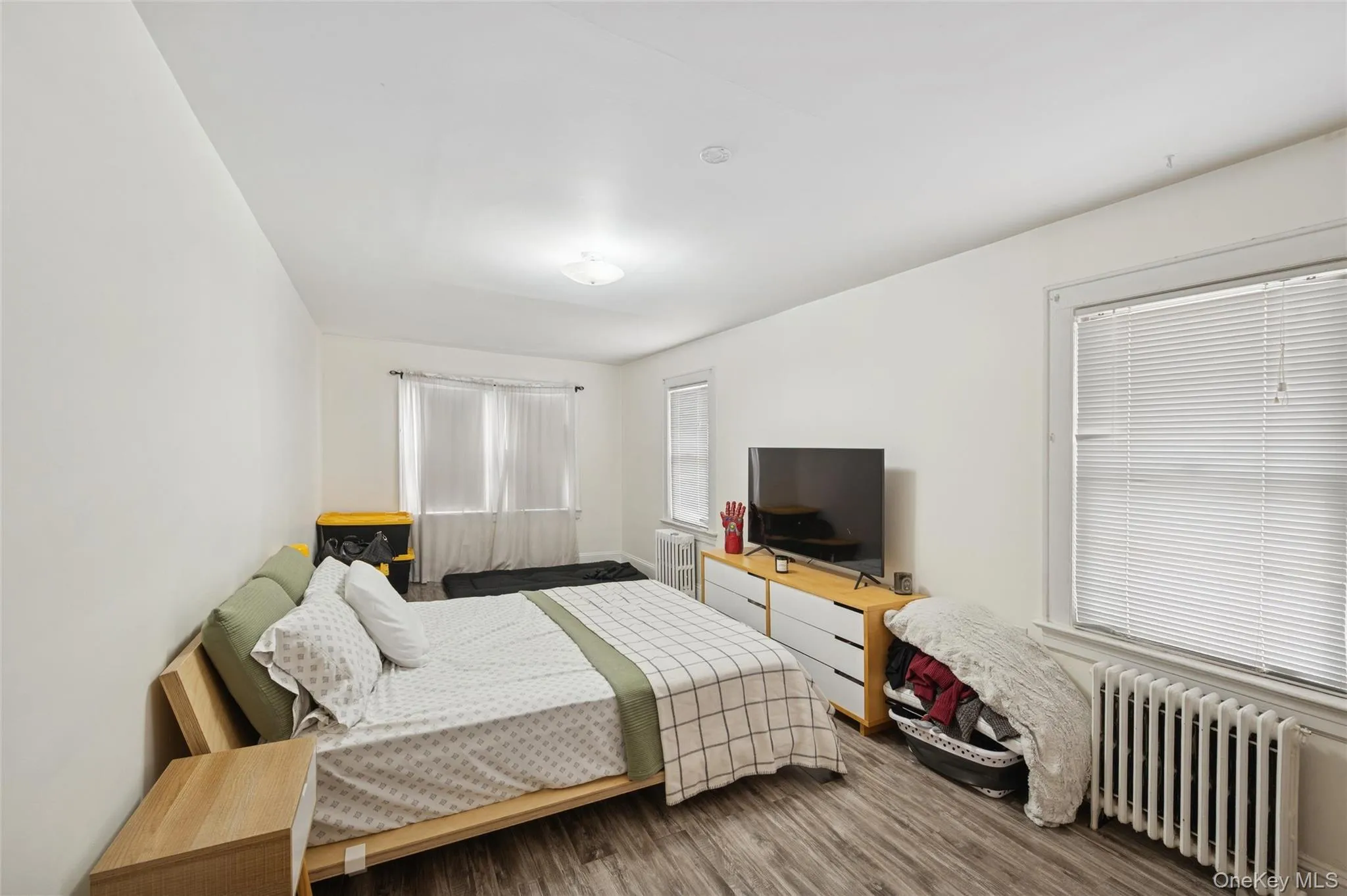 Bedroom featuring radiator heating unit and wood finished floors Bedroom featuring radiator heating unit and wood finished floors