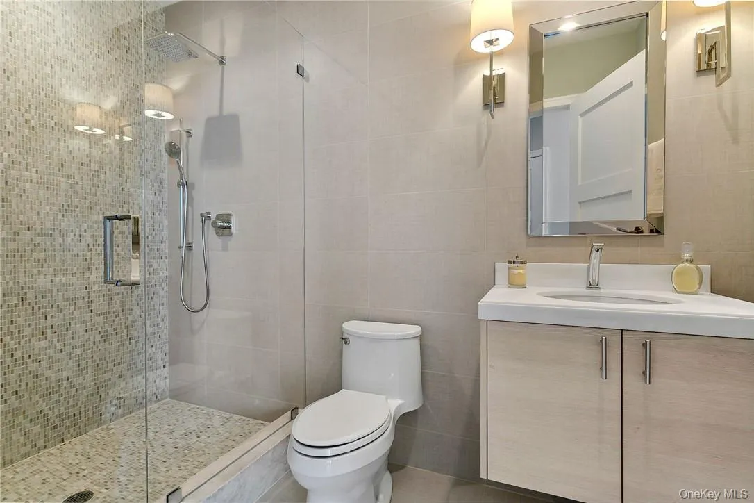 Bathroom with walk in shower, tile walls, vanity, and toilet Bathroom with walk in shower, tile walls, vanity, and toilet