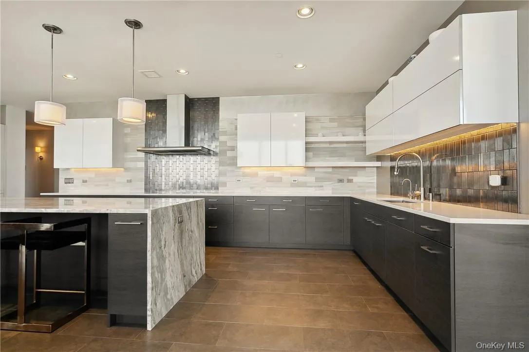 Kitchen featuring decorative backsplash, white cabinetry, wall chimney exhaust hood, decorative light fixtures, and sink Kitchen featuring decorative backsplash, white cabinetry, wall chimney exhaust hood, decorative light fixtures, and sink