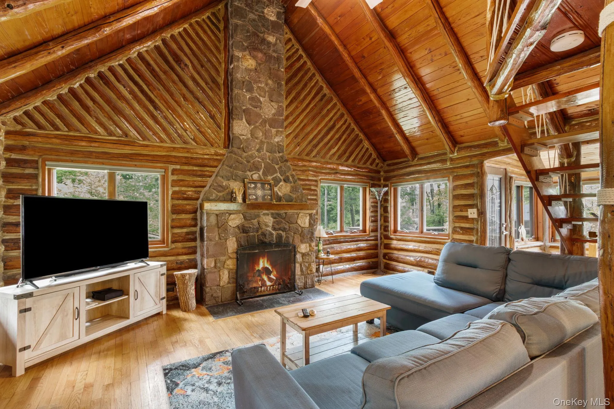Vaulted great room with a gas fireplace, wrapped in windows that overlook the yard and peaceful woods beyond. Vaulted great room with a gas fireplace, wrapped in windows that overlook the yard and peaceful woods beyond.
