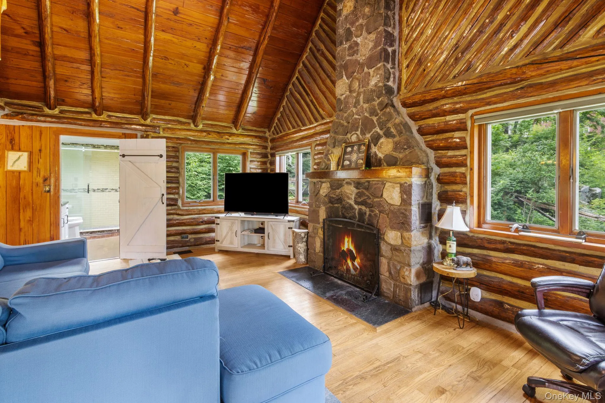 Vaulted great room with a gas fireplace, wrapped in windows that overlook the yard and peaceful woods beyond. Vaulted great room with a gas fireplace, wrapped in windows that overlook the yard and peaceful woods beyond.