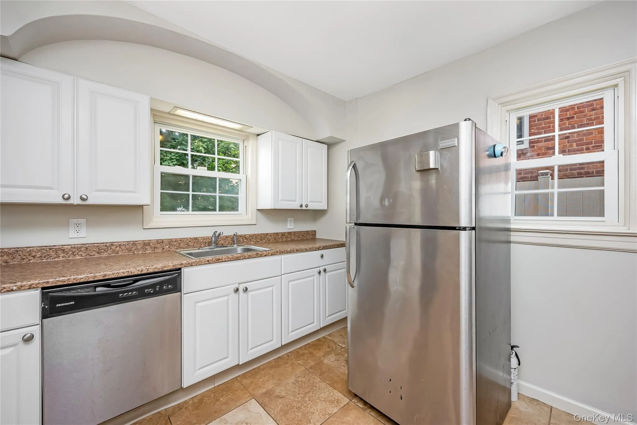 Kitchen featuring white cabinetry, a stainless steel refrigerator, and stainless steel dishwasher Kitchen featuring white cabinetry, a stainless steel refrigerator, and stainless steel dishwasher