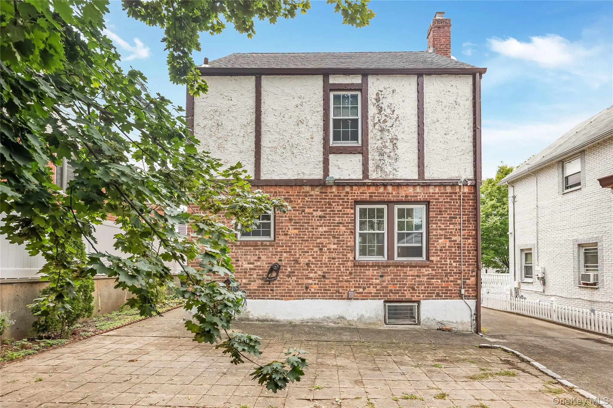 Brick and stucco exterior featuring multiple windows and a chimney Brick and stucco exterior featuring multiple windows and a chimney