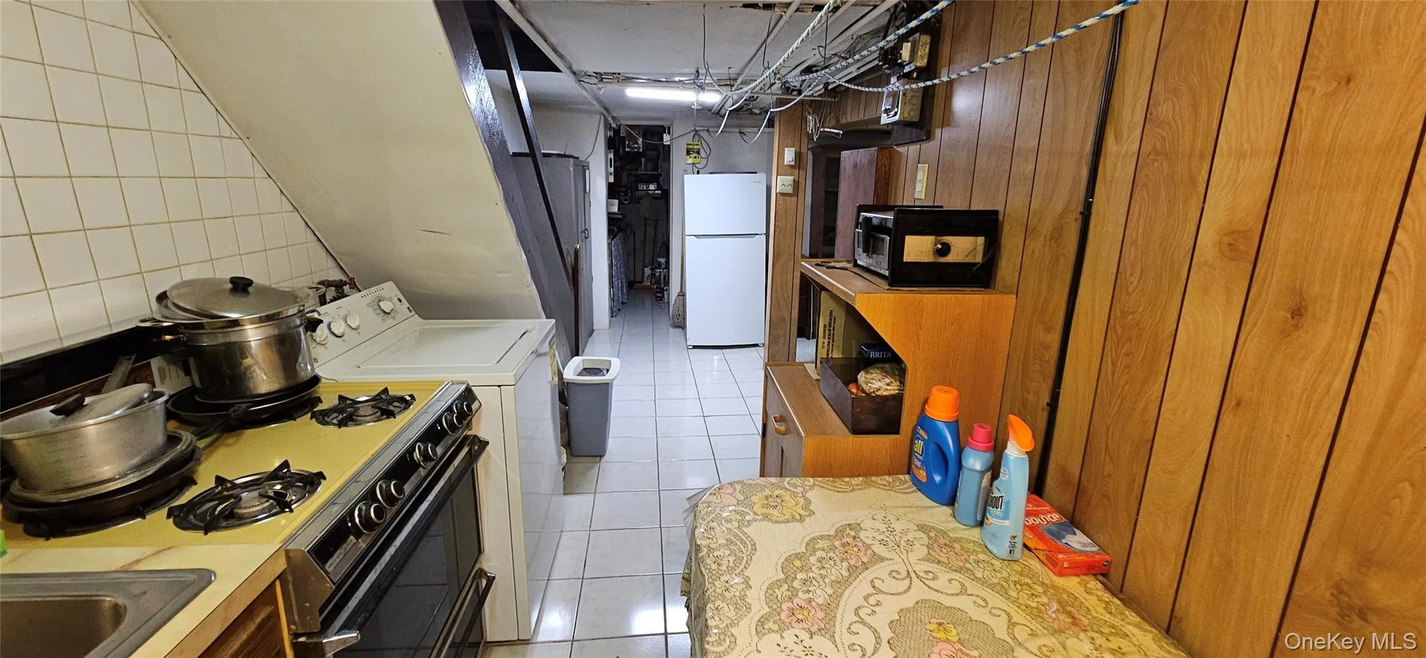 Kitchen with white appliances, light tile patterned flooring, light countertops, and independent washer and dryer Kitchen with white appliances, light tile patterned flooring, light countertops, and independent washer and dryer