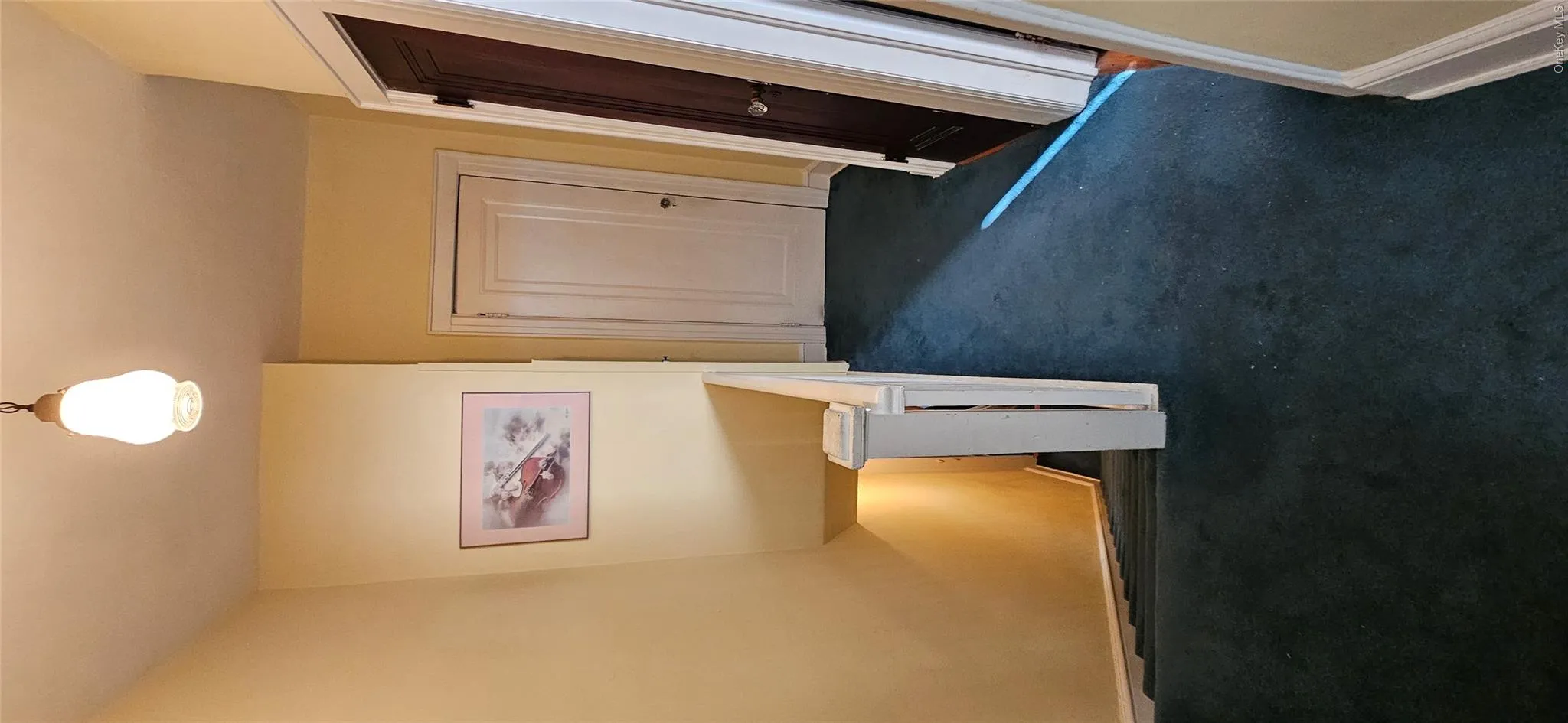 Hallway with an upstairs landing and dark colored carpet Hallway with an upstairs landing and dark colored carpet