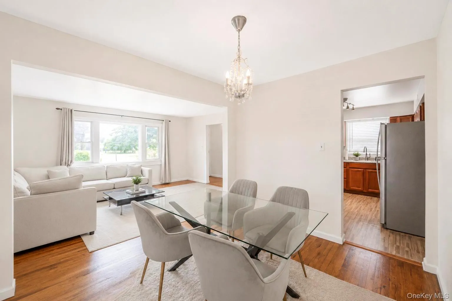Dining area featuring a crystal chandelier, wood-finish flooring, and an open entryway to the living area Dining area featuring a crystal chandelier, wood-finish flooring, and an open entryway to the living area