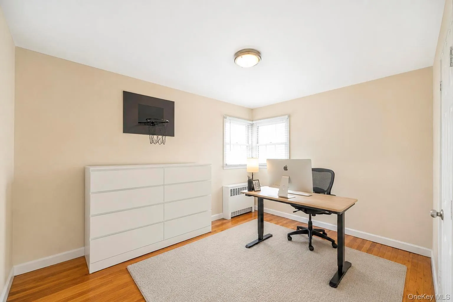 Room featuring wood-finish flooring, neutral wall paint, and a corner window with horizontal blinds Room featuring wood-finish flooring, neutral wall paint, and a corner window with horizontal blinds