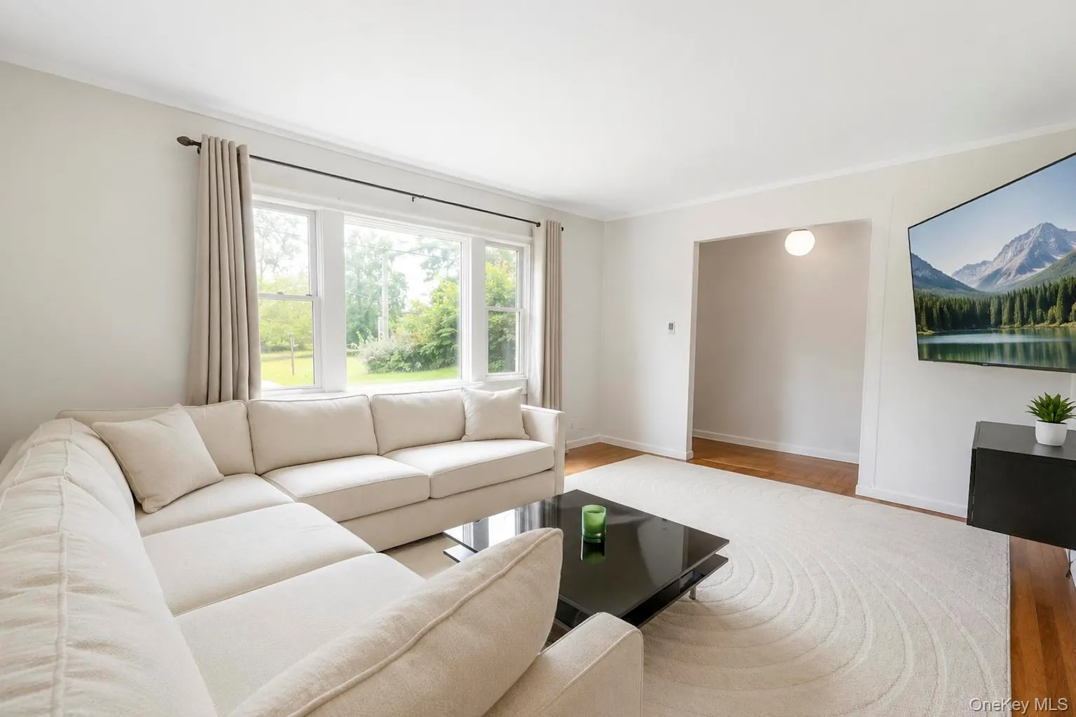 Living area featuring abundant natural light from a large multi-pane window, bright white walls, and a recessed doorway Living area featuring abundant natural light from a large multi-pane window, bright white walls, and a recessed doorway