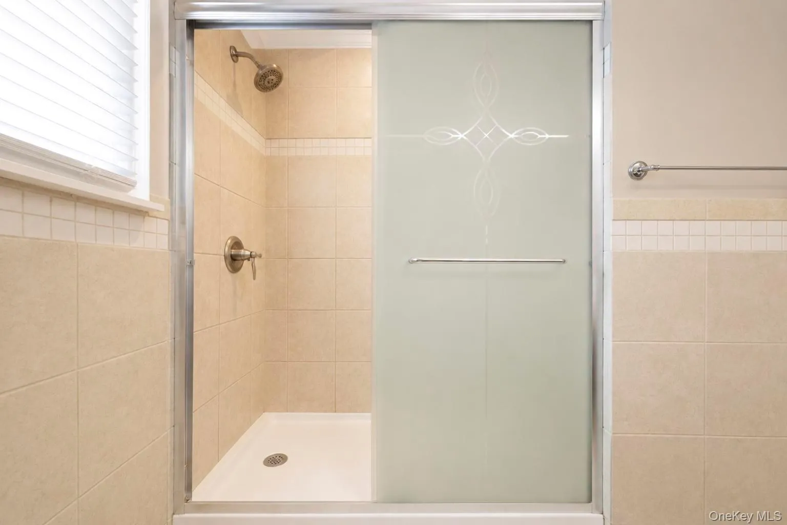 Shower enclosure featuring frosted glass sliding doors with decorative etching Shower enclosure featuring frosted glass sliding doors with decorative etching