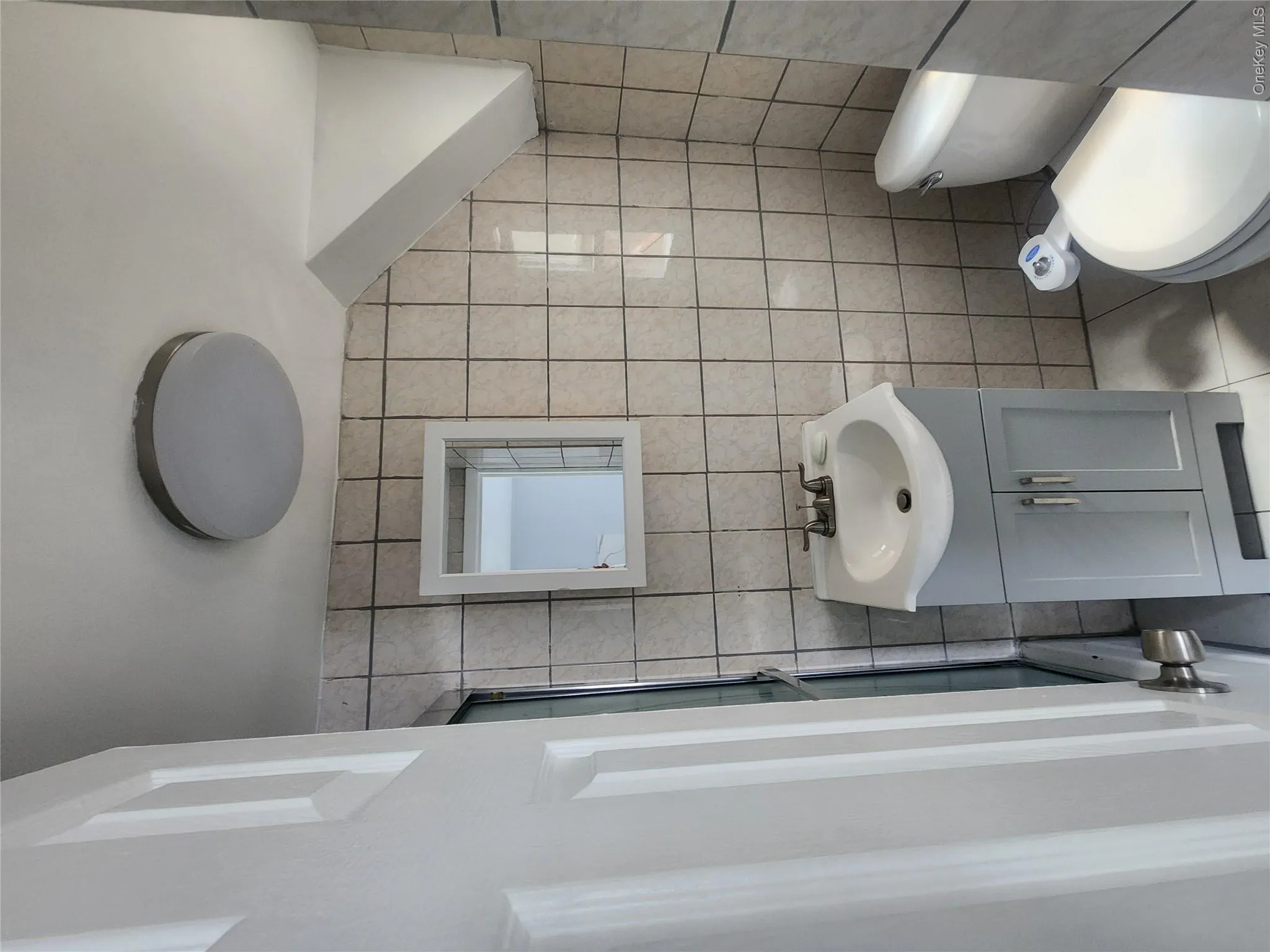 Compact bathroom featuring ceramic tile walls and flooring Compact bathroom featuring ceramic tile walls and flooring