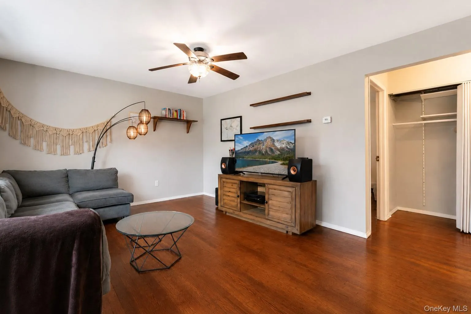 Living area featuring wood-finish flooring, a ceiling fan with integrated lighting, and neutral wall tones Living area featuring wood-finish flooring, a ceiling fan with integrated lighting, and neutral wall tones
