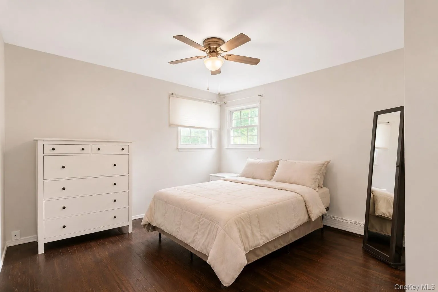 Bedroom #1 featuring dark wood-finish flooring, light neutral-toned walls, and a ceiling fan with integrated lighting Bedroom #1 featuring dark wood-finish flooring, light neutral-toned walls, and a ceiling fan with integrated lighting