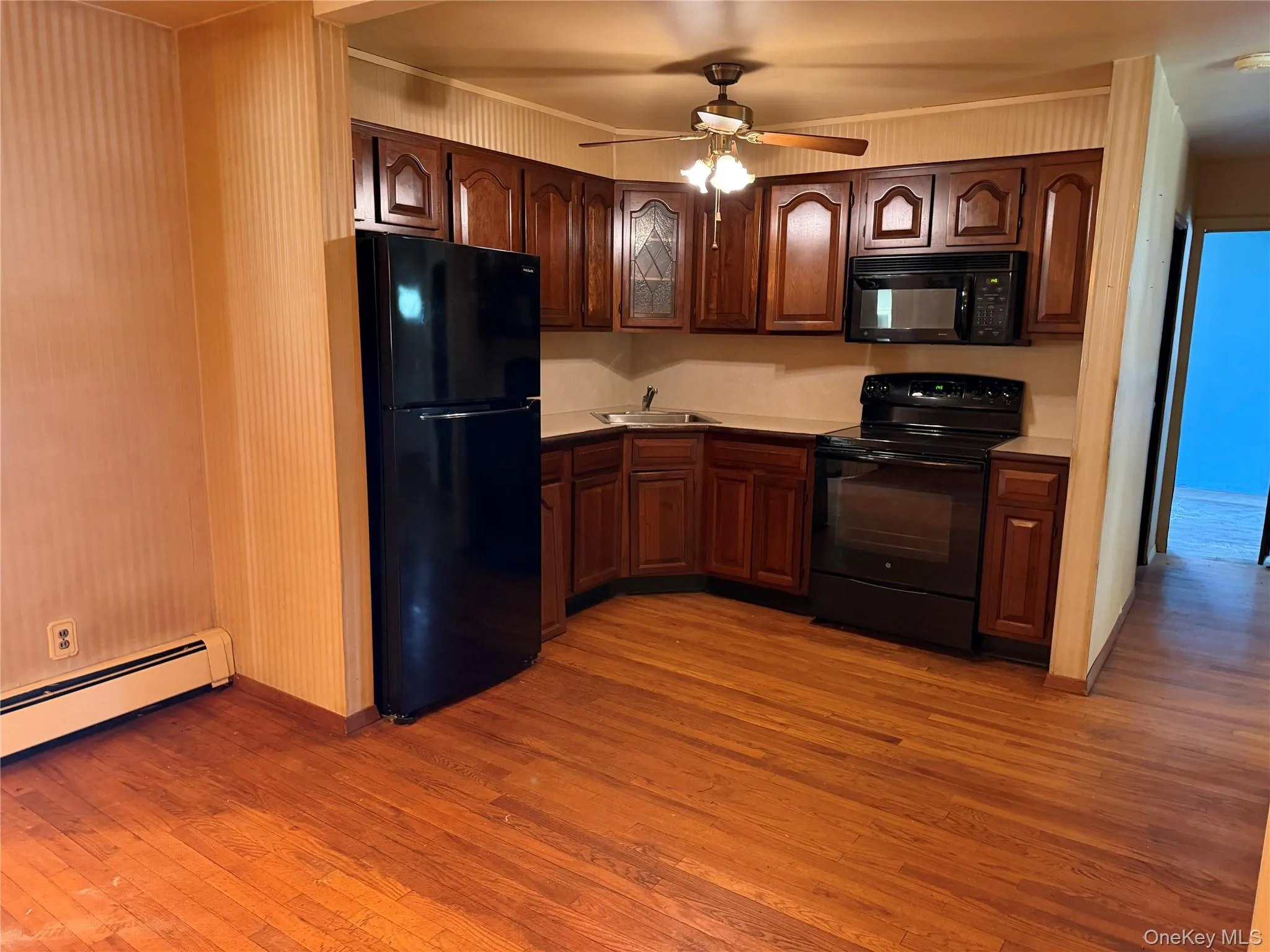 Kitchen featuring wood-finish flooring, dark wood cabinetry, and a ceiling fan Kitchen featuring wood-finish flooring, dark wood cabinetry, and a ceiling fan