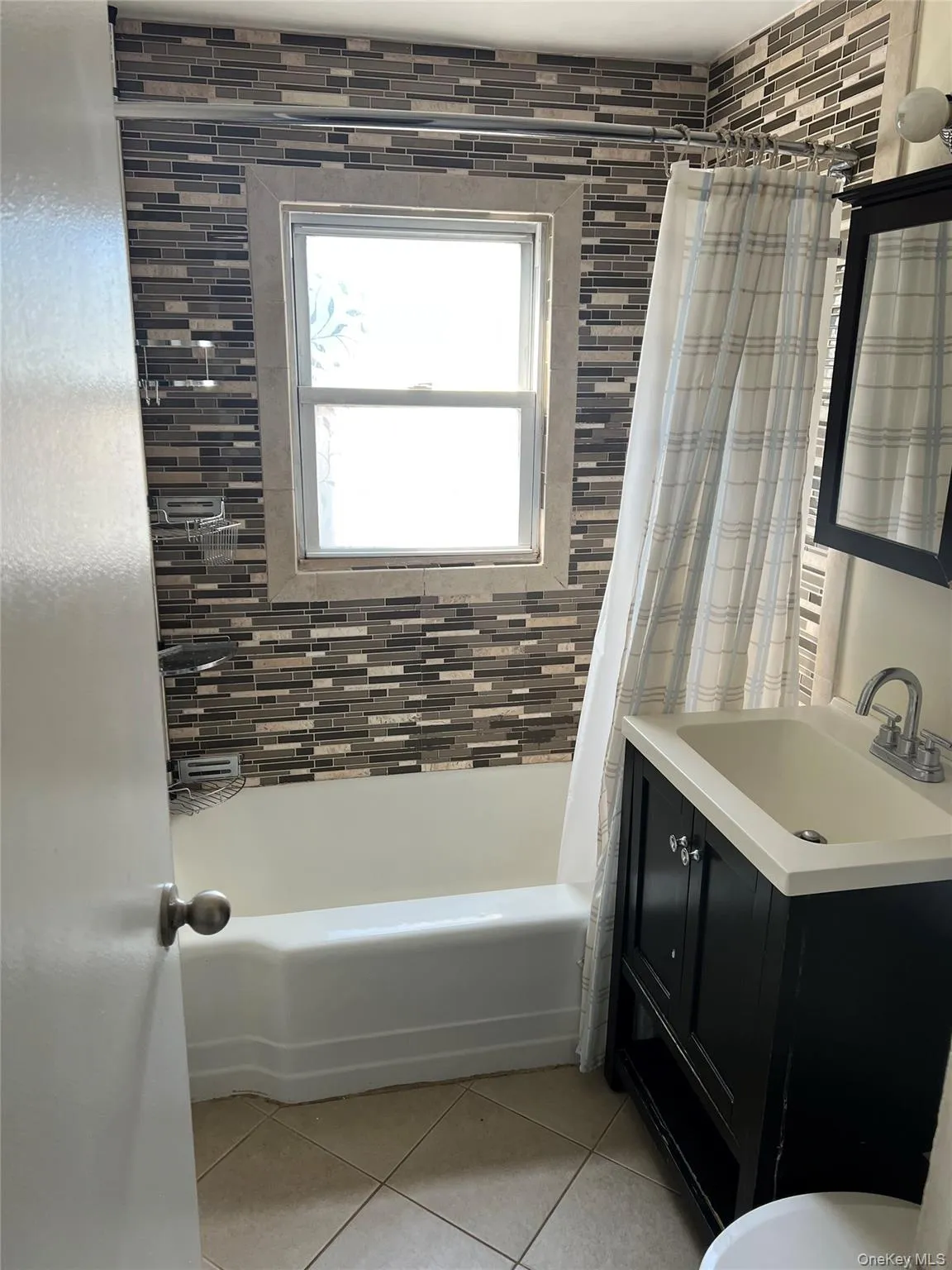 Full bathroom featuring shower / tub combo with curtain, vanity, and light tile patterned floors Full bathroom featuring shower / tub combo with curtain, vanity, and light tile patterned floors