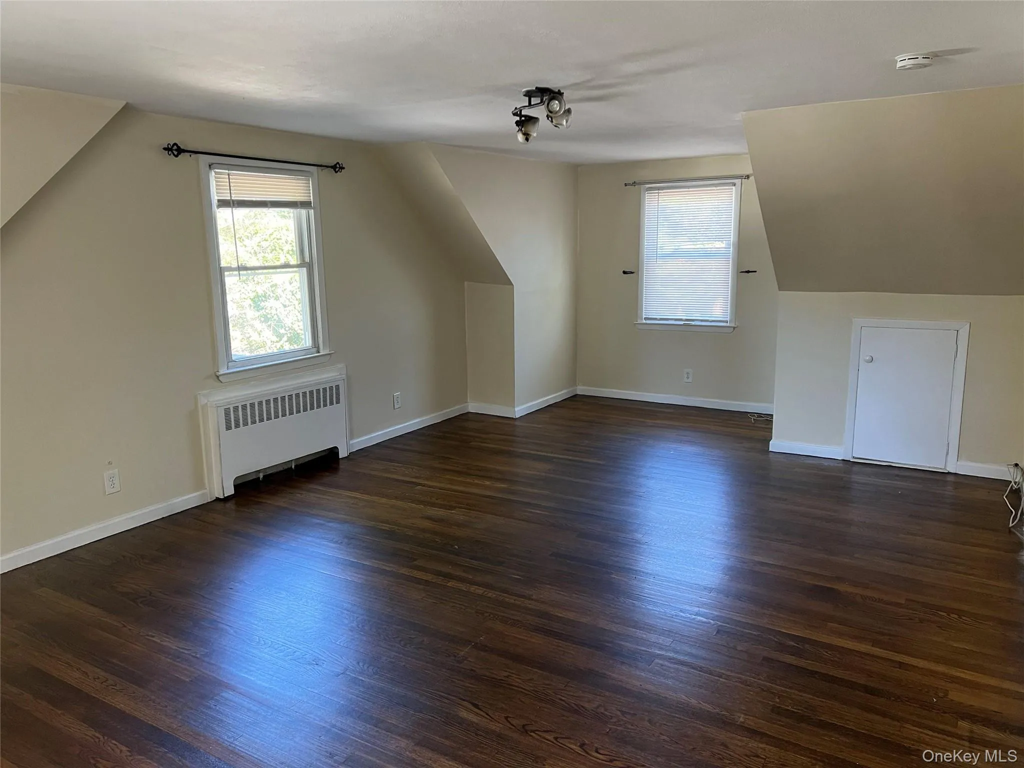 Bonus room with dark wood-type flooring, radiator heating unit, and plenty of natural light Bonus room with dark wood-type flooring, radiator heating unit, and plenty of natural light