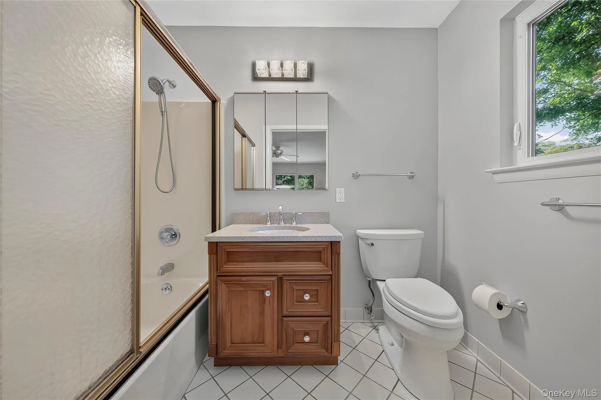 Bathroom featuring a wood-finish vanity with an integrated sink, a mirrored medicine cabinet, and shower sliding glass doors Bathroom featuring a wood-finish vanity with an integrated sink, a mirrored medicine cabinet, and shower sliding glass doors