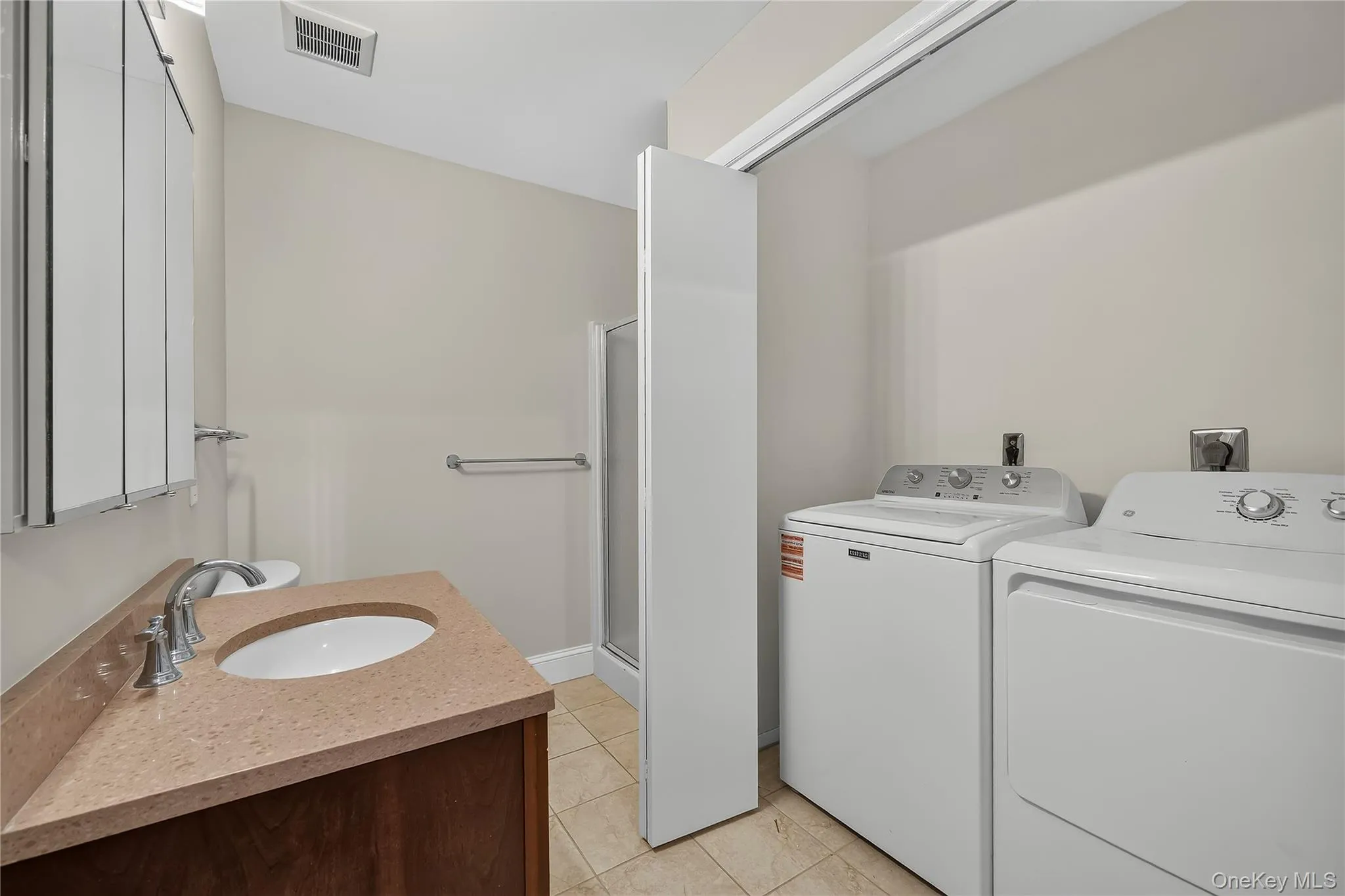 Laundry with full sized washer and dryer in spacious hall bathroom with bifold doors. Laundry with full sized washer and dryer in spacious hall bathroom with bifold doors.