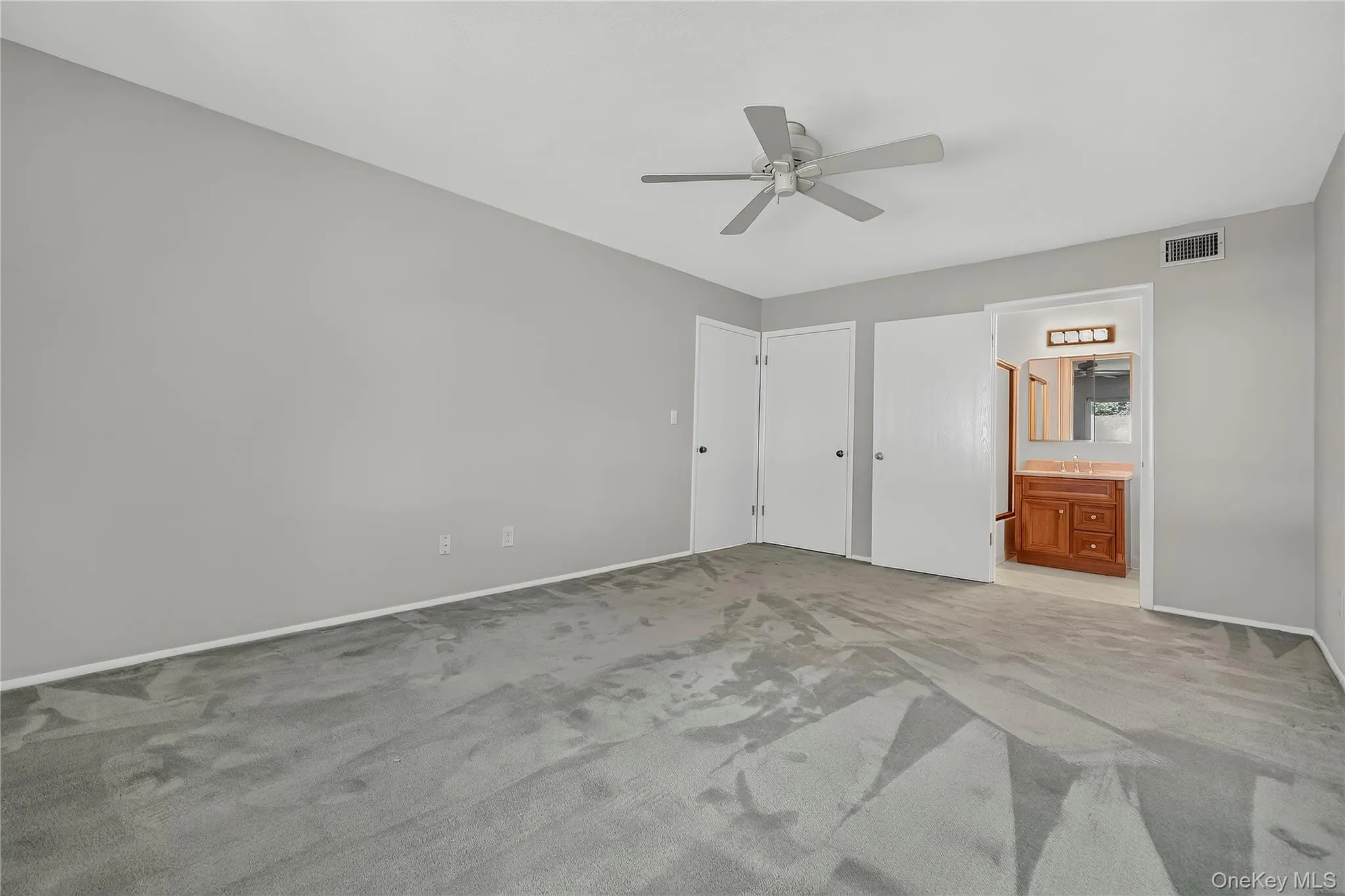 Primary bedroom with brand new carpeting, ceiling fan and large walk in closet. Primary bedroom with brand new carpeting, ceiling fan and large walk in closet.