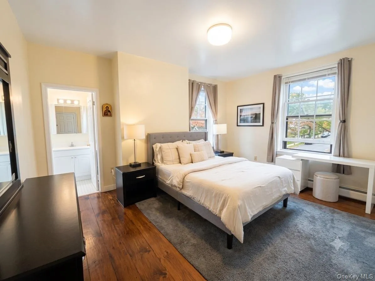 Spacious room featuring wood-finish flooring, light-colored walls, and a ceiling-mounted light fixture Spacious room featuring wood-finish flooring, light-colored walls, and a ceiling-mounted light fixture