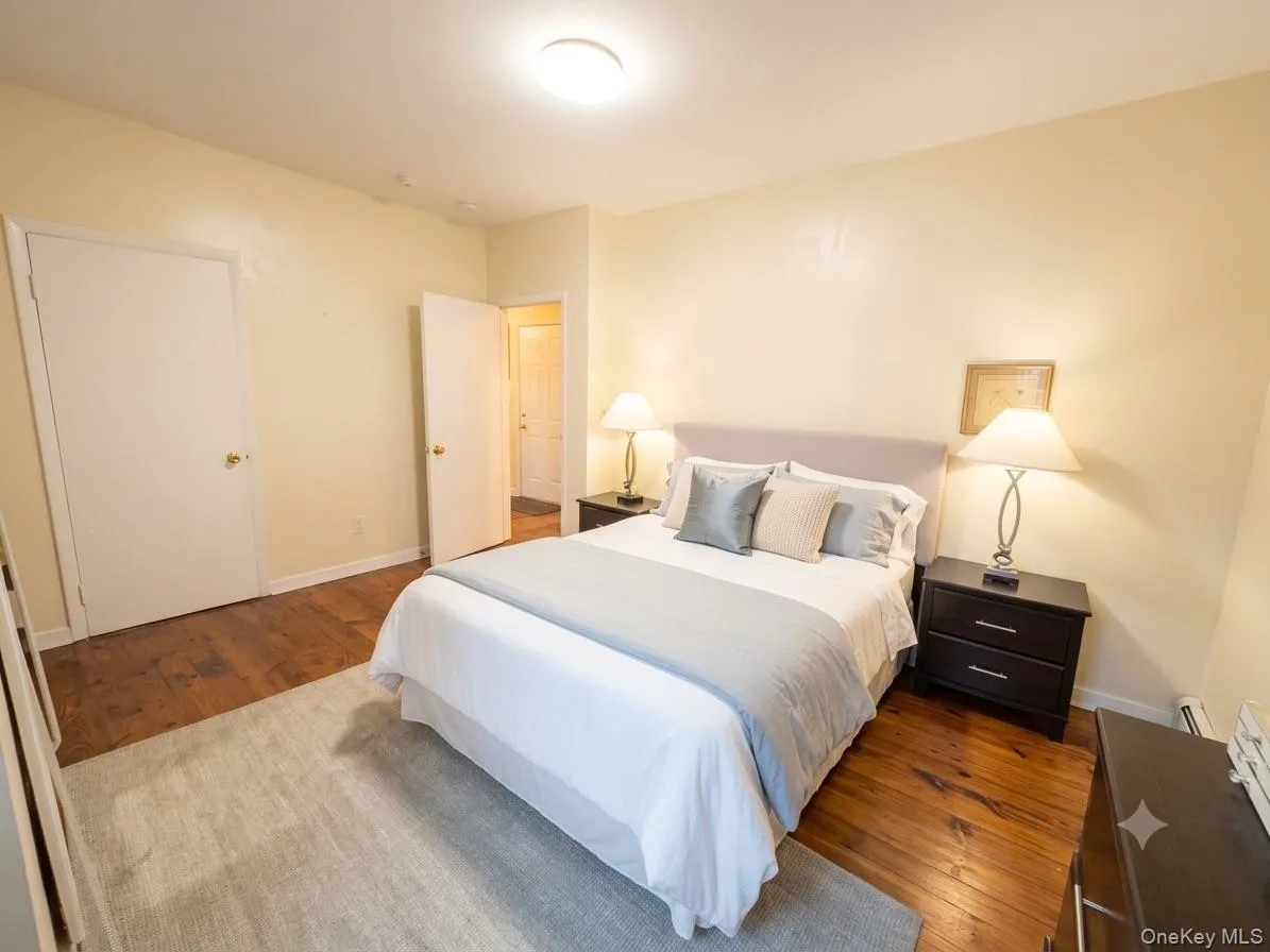 Bedroom featuring wood-finish flooring, light-toned walls, and a ceiling-mounted light fixture Bedroom featuring wood-finish flooring, light-toned walls, and a ceiling-mounted light fixture