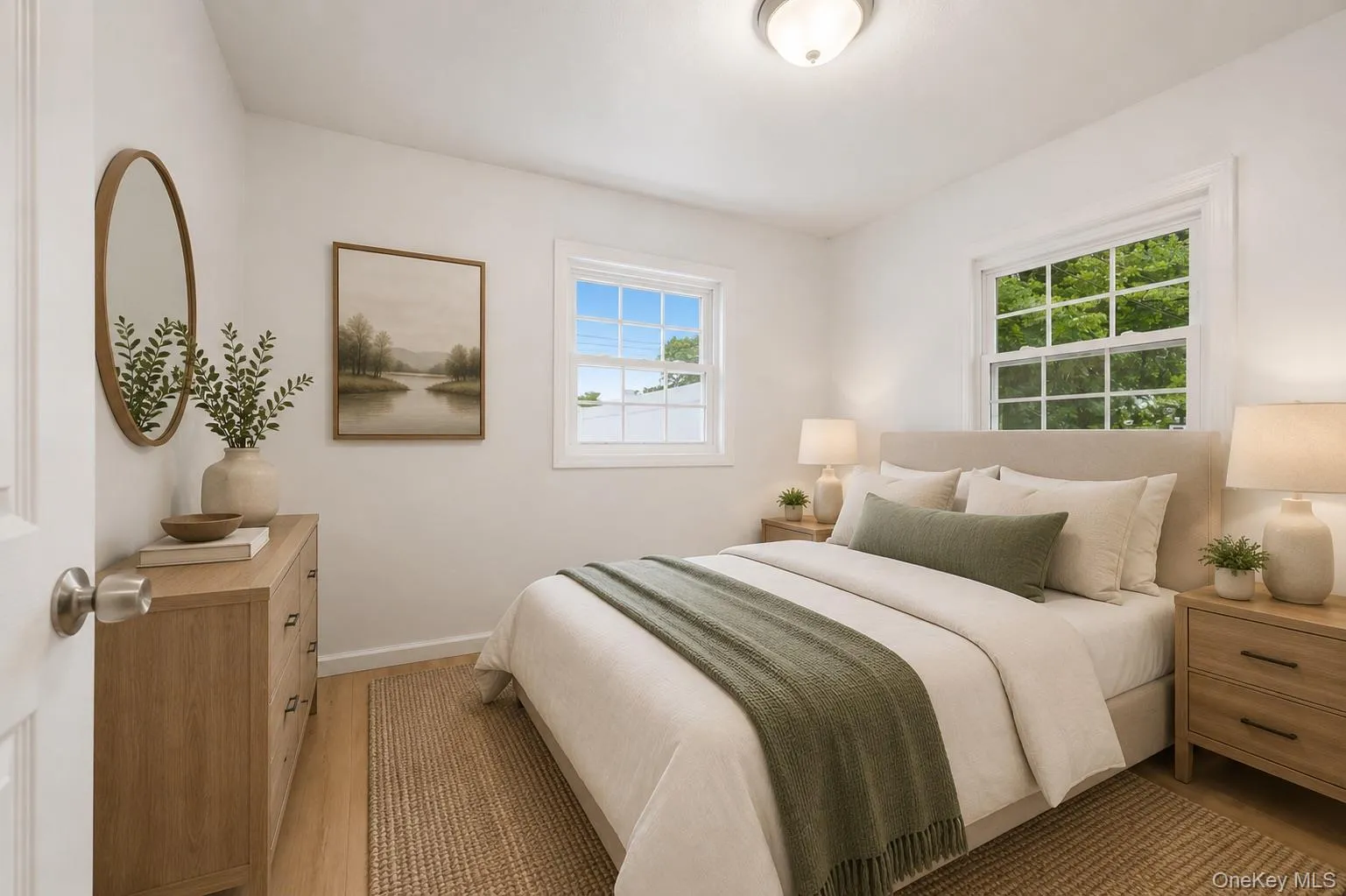 Bedroom featuring light wood-finish flooring, white walls, and a ceiling-mounted light fixture Bedroom featuring light wood-finish flooring, white walls, and a ceiling-mounted light fixture