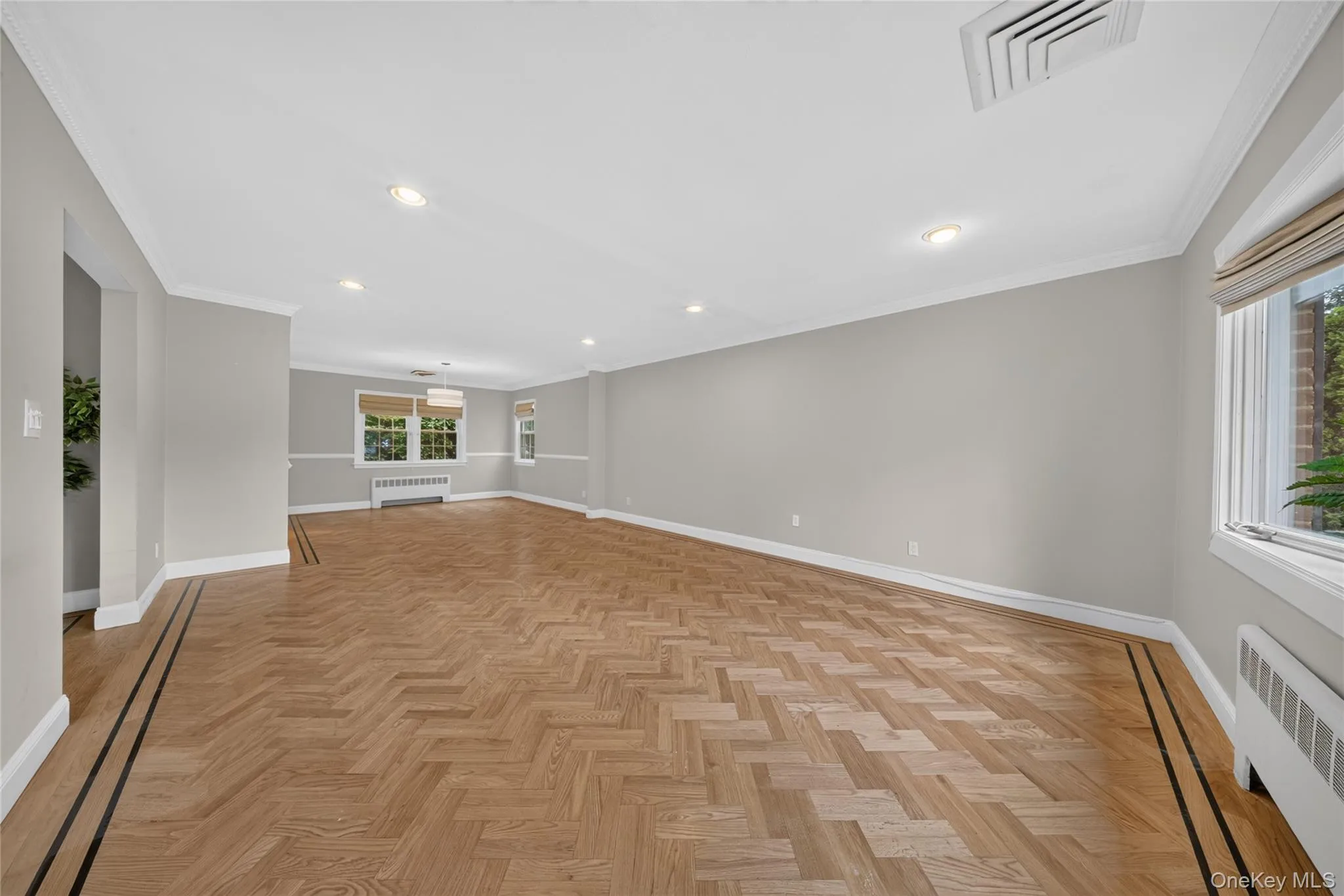 Expansive room featuring herringbone wood-finish flooring with a decorative border Expansive room featuring herringbone wood-finish flooring with a decorative border