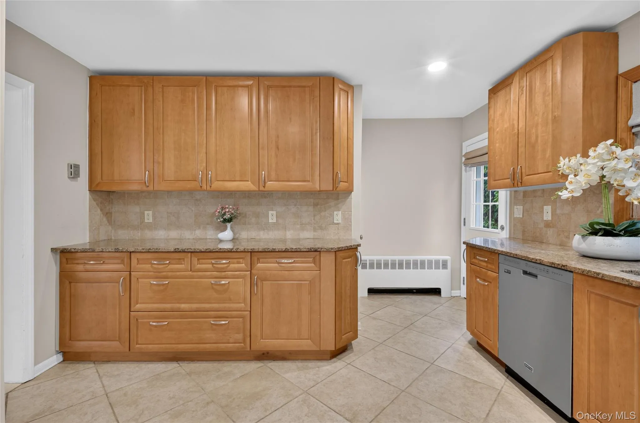 Kitchen featuring wood cabinetry, stone countertops, a tile backsplash, and tile flooring Kitchen featuring wood cabinetry, stone countertops, a tile backsplash, and tile flooring