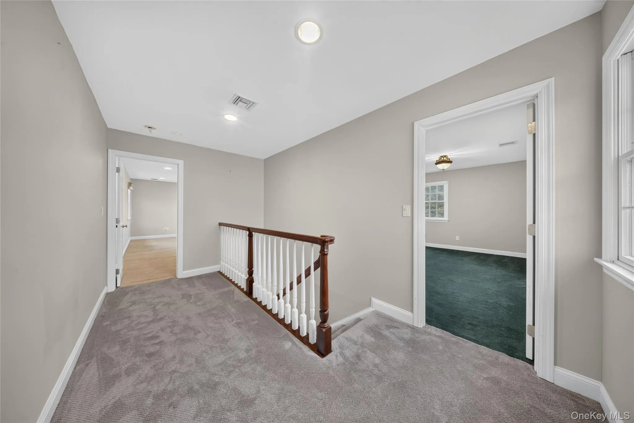 Upper-level landing featuring neutral gray wall paint and gray carpeting Upper-level landing featuring neutral gray wall paint and gray carpeting