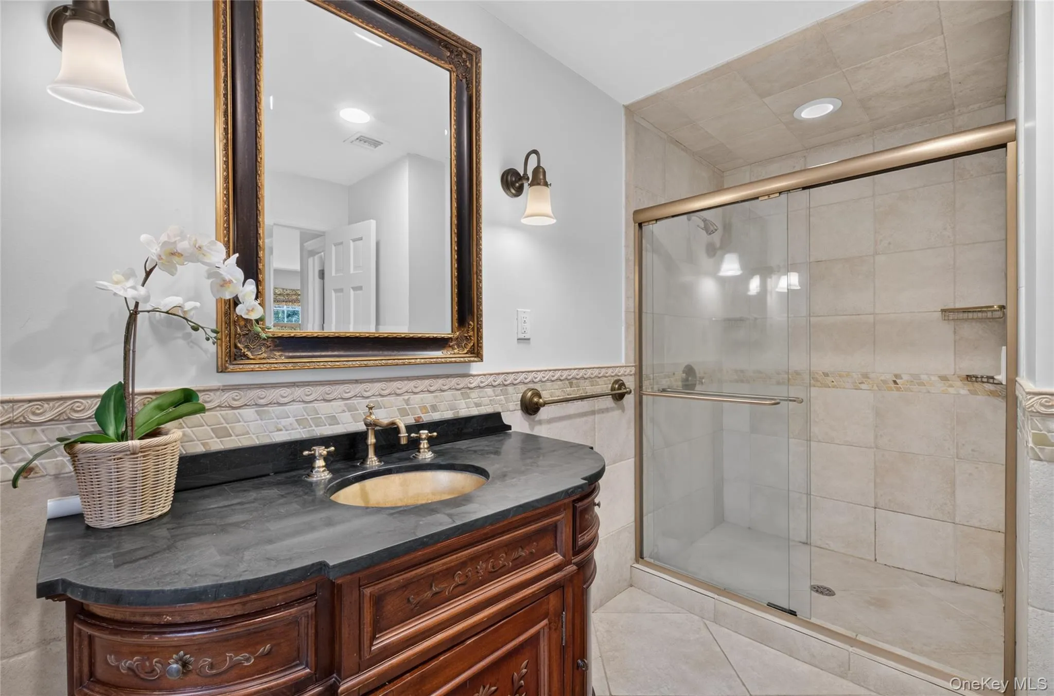 Bathroom featuring a wood-finish vanity with a dark countertop and undermount sink Bathroom featuring a wood-finish vanity with a dark countertop and undermount sink