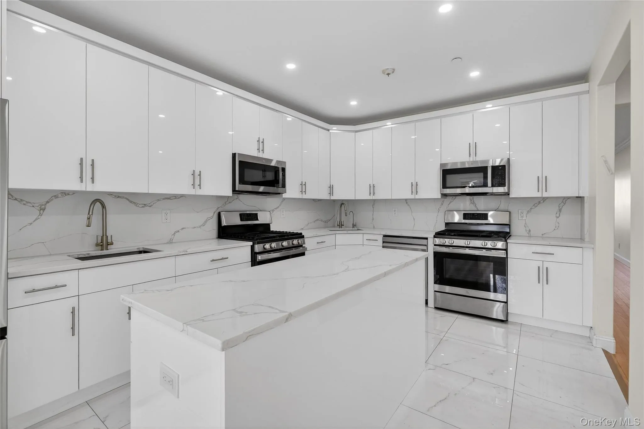 Kitchen featuring stainless steel appliances, tasteful backsplash, a kitchen island, light stone countertops, and light marble finish floors Kitchen featuring stainless steel appliances, tasteful backsplash, a kitchen island, light stone countertops, and light marble finish floors