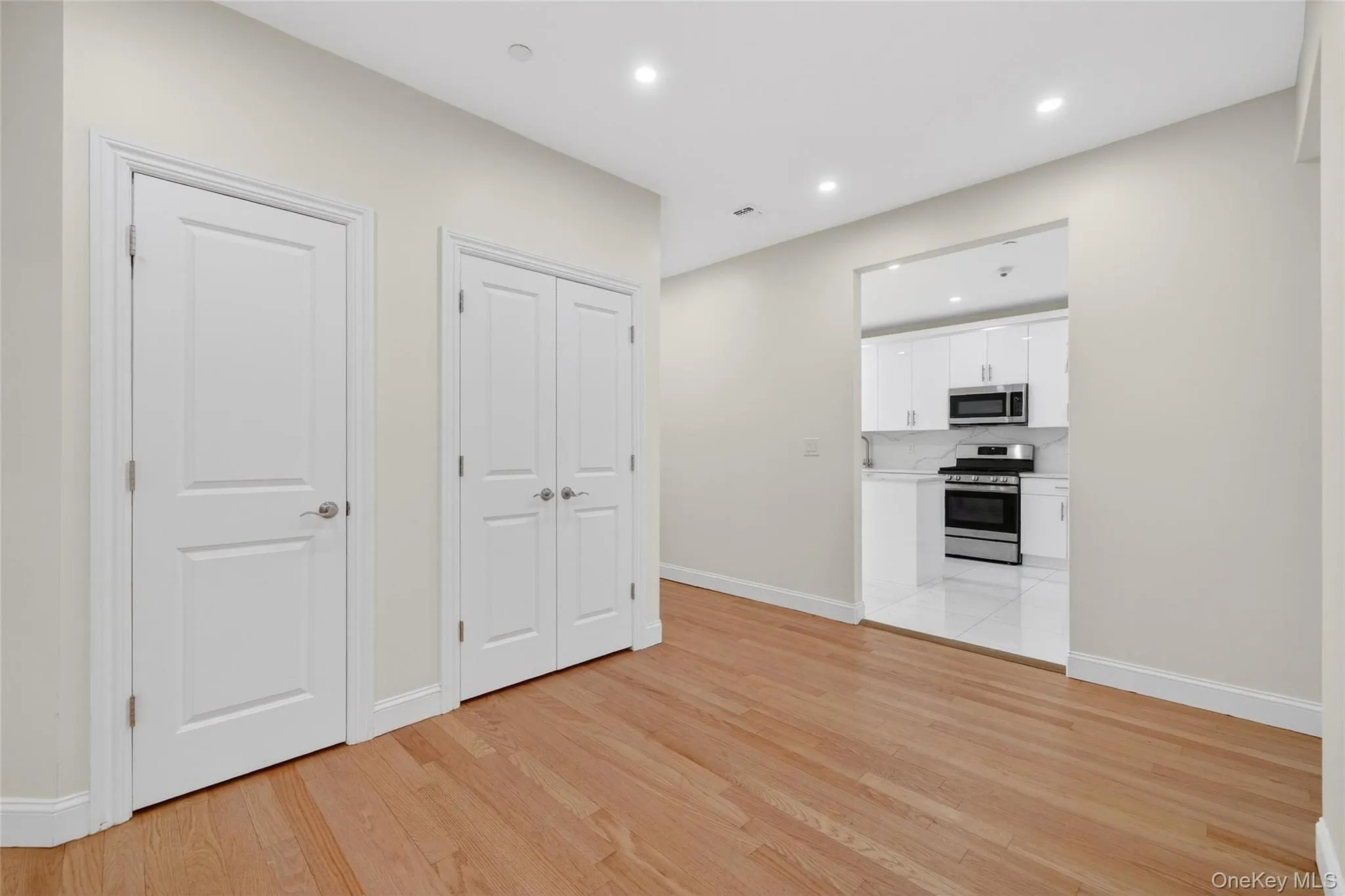 Kitchen with white cabinetry, appliances with stainless steel finishes, light countertops, light wood-type flooring, and recessed lighting Kitchen with white cabinetry, appliances with stainless steel finishes, light countertops, light wood-type flooring, and recessed lighting