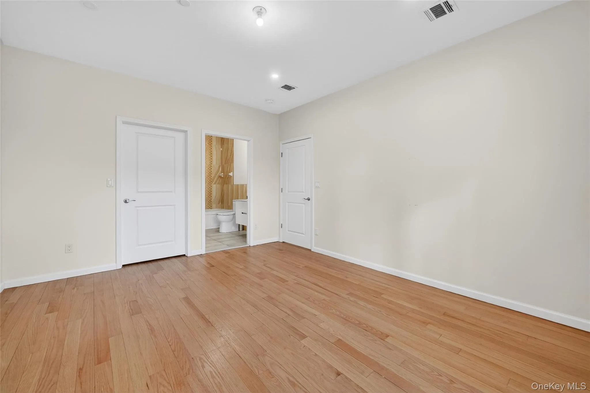 Unfurnished bedroom featuring light wood finished floors, connected bathroom, and recessed lighting Unfurnished bedroom featuring light wood finished floors, connected bathroom, and recessed lighting