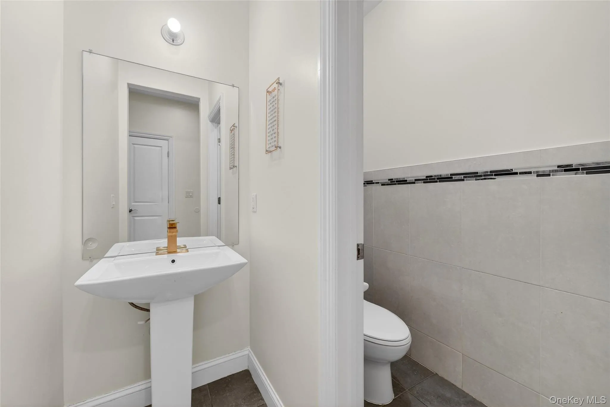 Bathroom with tile walls, dark tile patterned flooring, and wainscoting Bathroom with tile walls, dark tile patterned flooring, and wainscoting