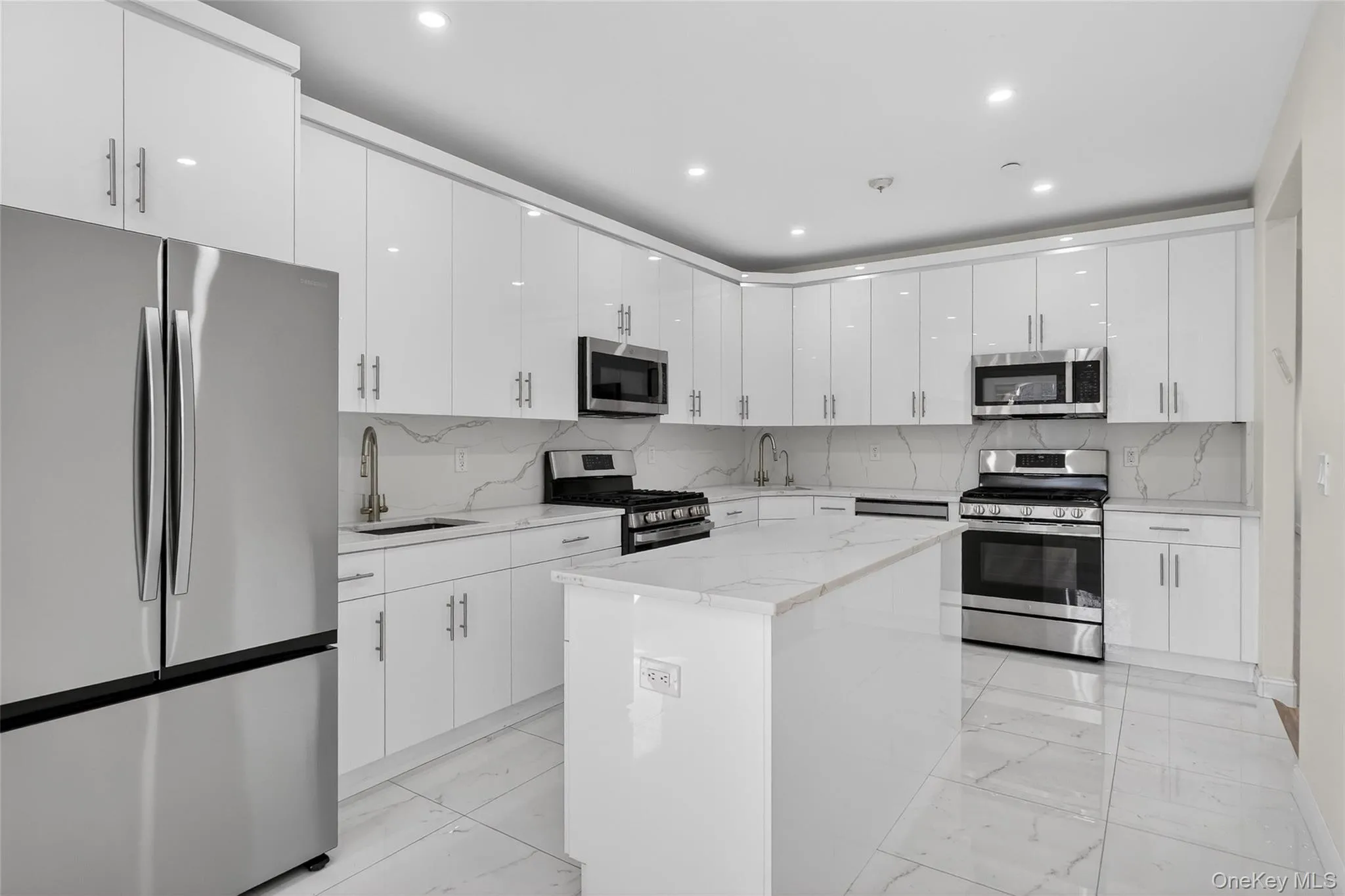 Kitchen featuring appliances with stainless steel finishes, light marble finish floors, white cabinetry, tasteful backsplash, and recessed lighting Kitchen featuring appliances with stainless steel finishes, light marble finish floors, white cabinetry, tasteful backsplash, and recessed lighting