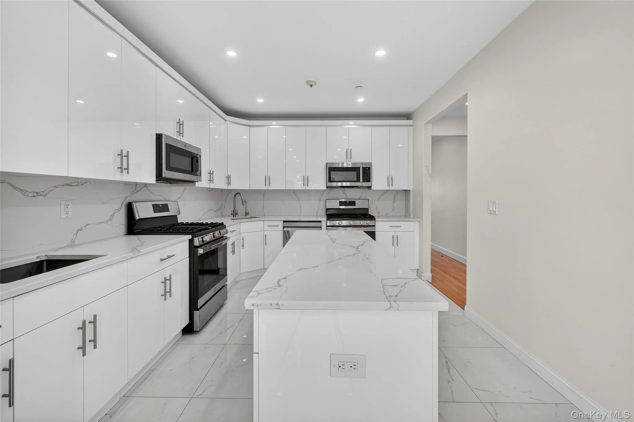 Kitchen with stainless steel appliances, a center island, light marble finish floors, tasteful backsplash, and recessed lighting Kitchen with stainless steel appliances, a center island, light marble finish floors, tasteful backsplash, and recessed lighting
