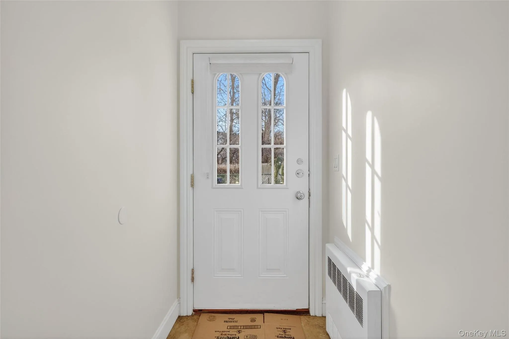 Doorway to outside with radiator and baseboards Doorway to outside with radiator and baseboards