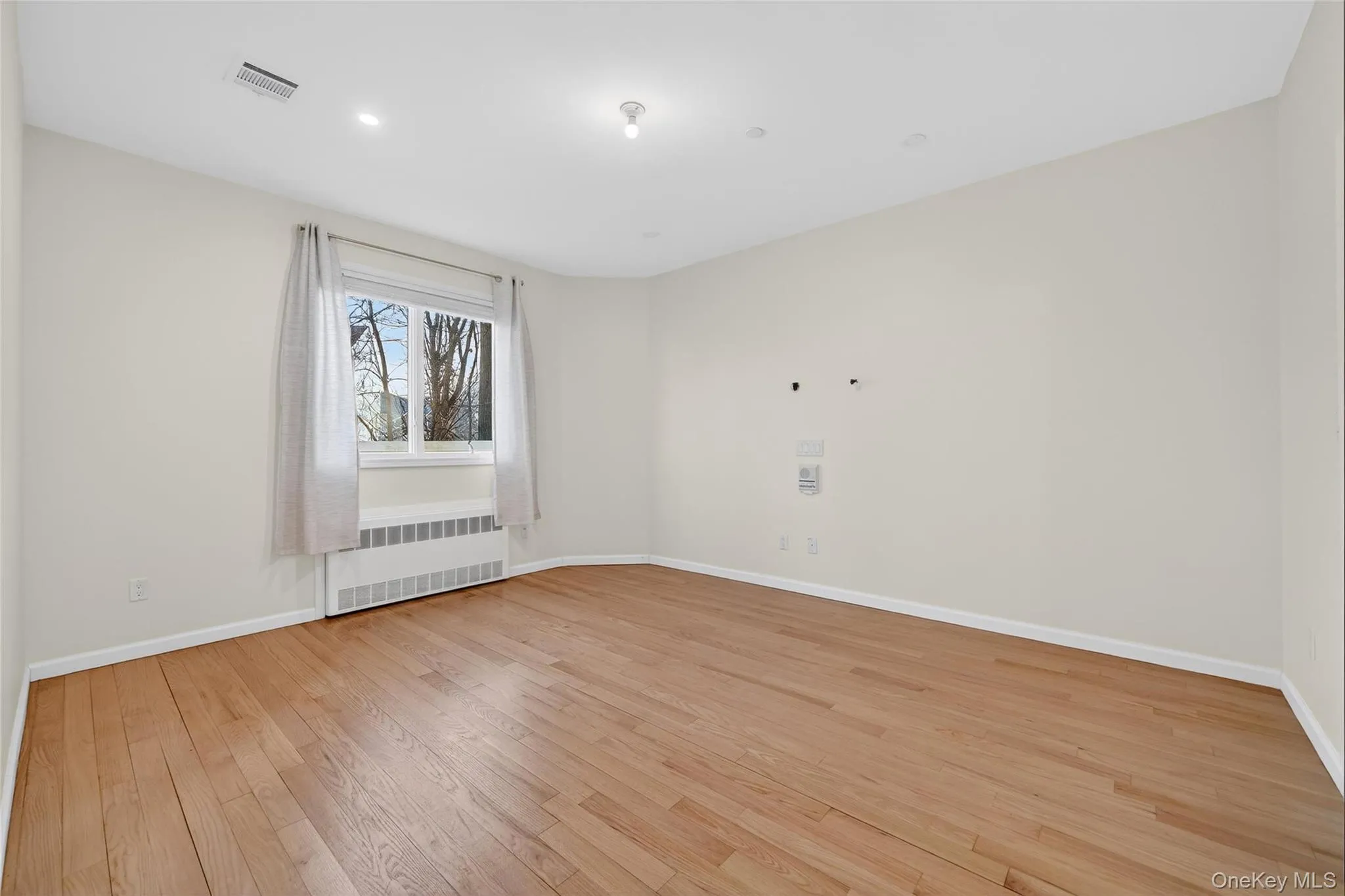 Spare room with light wood-style floors and radiator Spare room with light wood-style floors and radiator