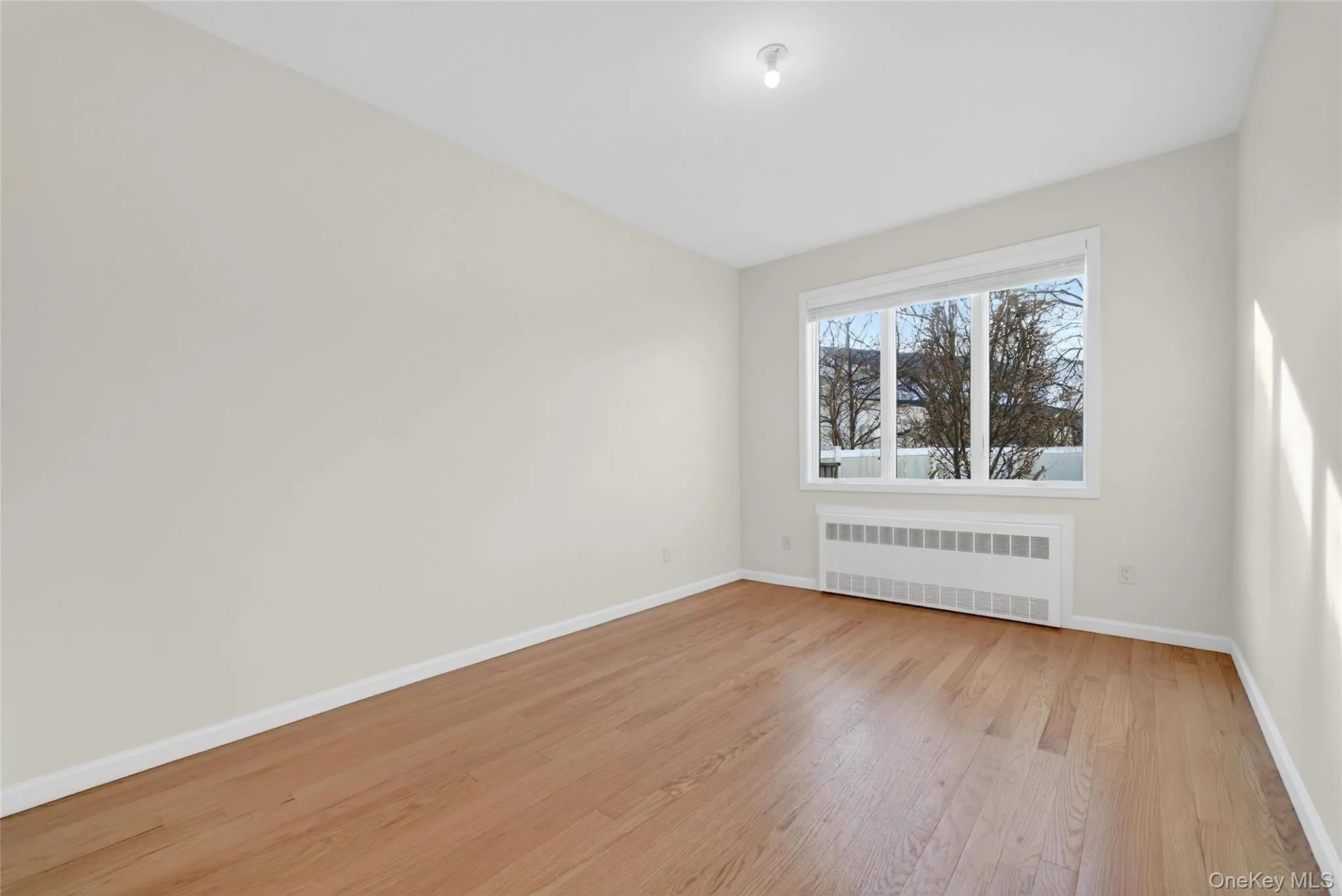 Empty room with radiator and light wood-style flooring Empty room with radiator and light wood-style flooring