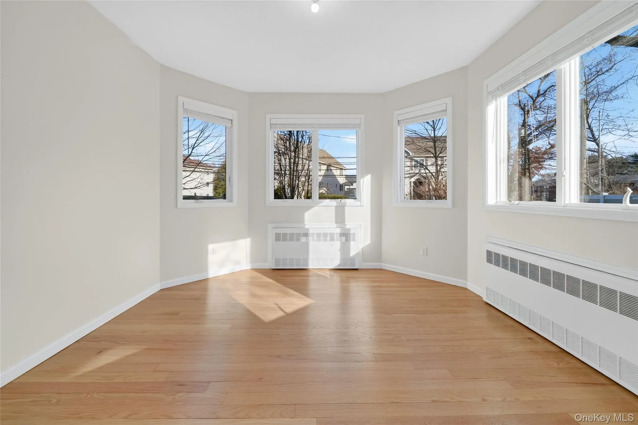 Unfurnished room with radiator heating unit and light wood-style flooring Unfurnished room with radiator heating unit and light wood-style flooring