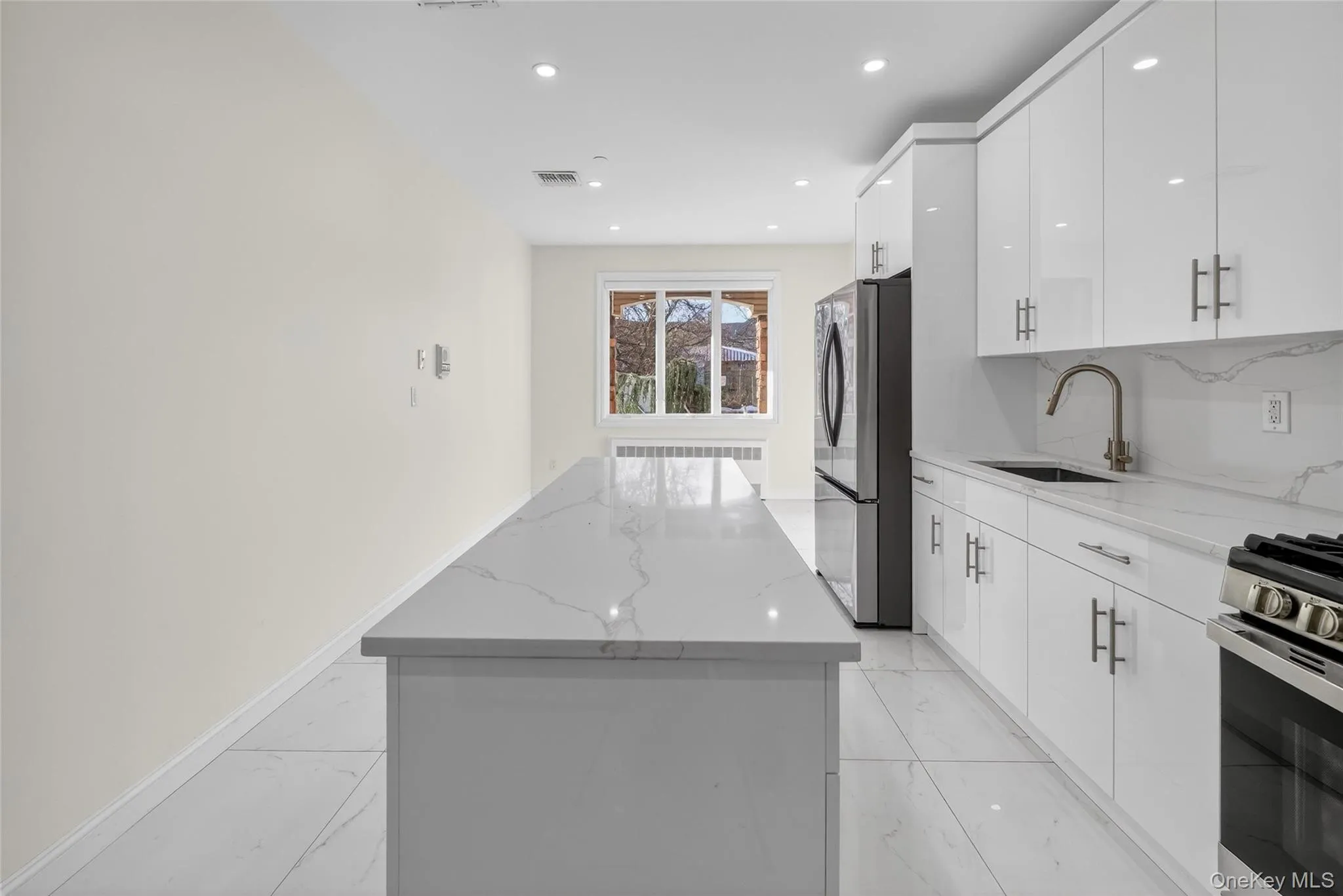 Kitchen featuring a center island, light stone countertops, appliances with stainless steel finishes, white cabinetry, and recessed lighting Kitchen featuring a center island, light stone countertops, appliances with stainless steel finishes, white cabinetry, and recessed lighting