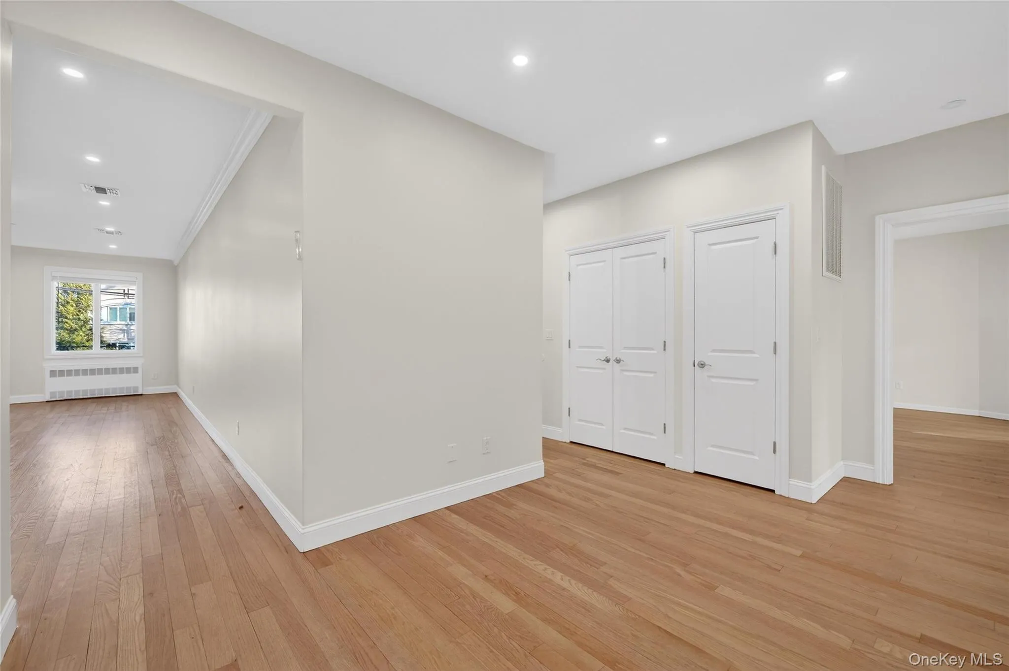 Hall featuring recessed lighting, light wood-style flooring, radiator heating unit, and crown molding Hall featuring recessed lighting, light wood-style flooring, radiator heating unit, and crown molding
