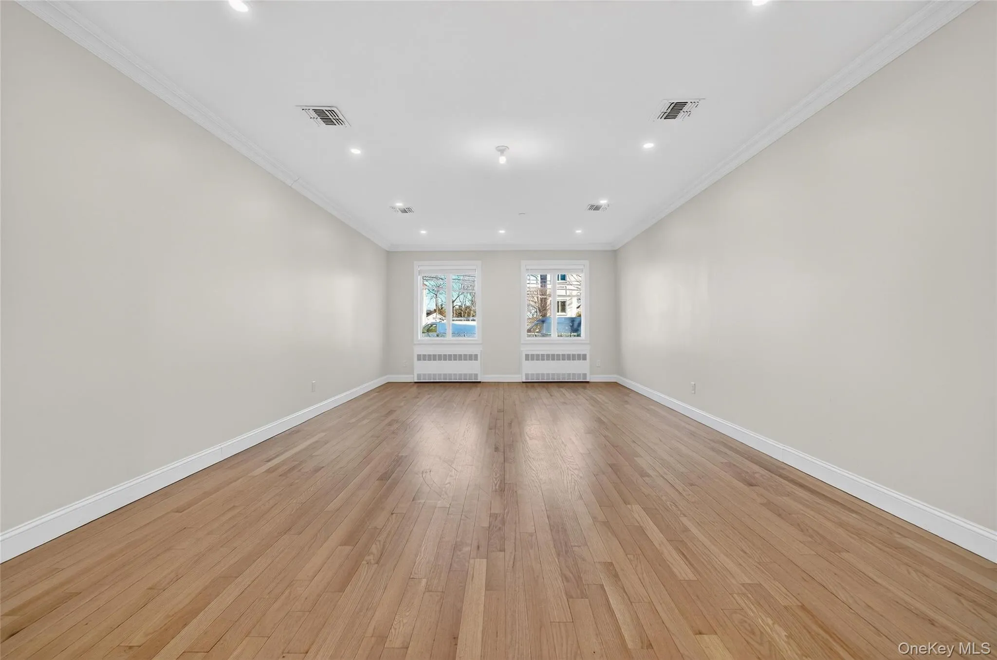 Spare room with ornamental molding, light wood-type flooring, radiator, and recessed lighting Spare room with ornamental molding, light wood-type flooring, radiator, and recessed lighting