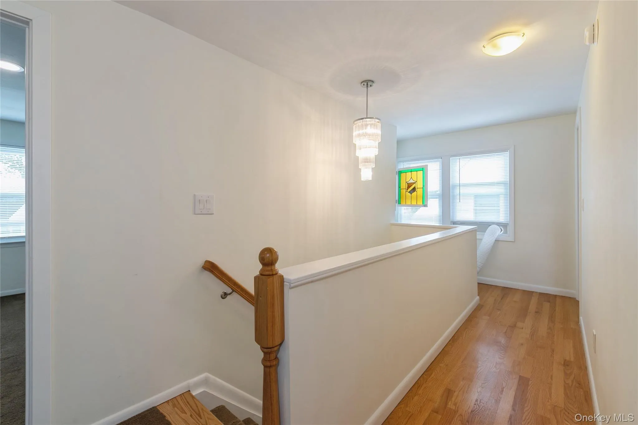 Spacious upper-level hallway with hardwood floors, abundant natural light, and an elegant chandelier that enhances the home's welcoming feel. Spacious upper-level hallway with hardwood floors, abundant natural light, and an elegant chandelier that enhances the home's welcoming feel.