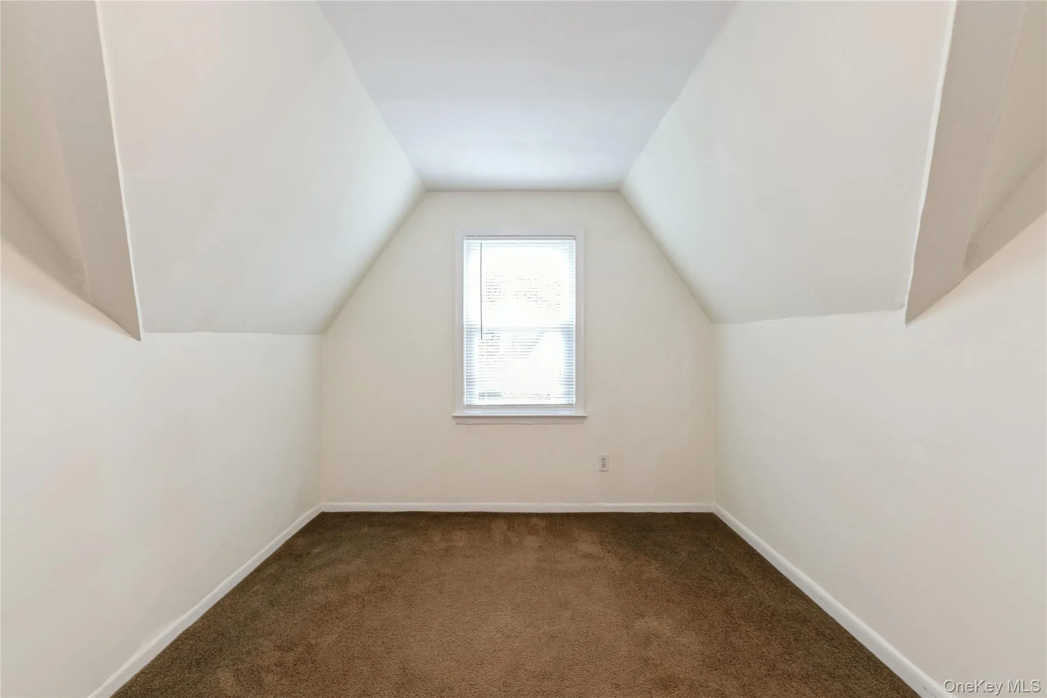 Cozy primary bedroom with soft carpeting, natural light, and charming sloped ceilings that add warmth and character to the space. Cozy primary bedroom with soft carpeting, natural light, and charming sloped ceilings that add warmth and character to the space.