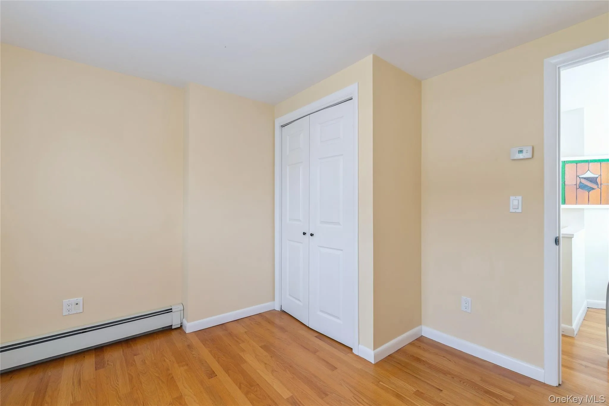 Bedroom featuring hardwood floors and a spacious double-door closet, providing ample storage and a clean, functional layout. Bedroom featuring hardwood floors and a spacious double-door closet, providing ample storage and a clean, functional layout.