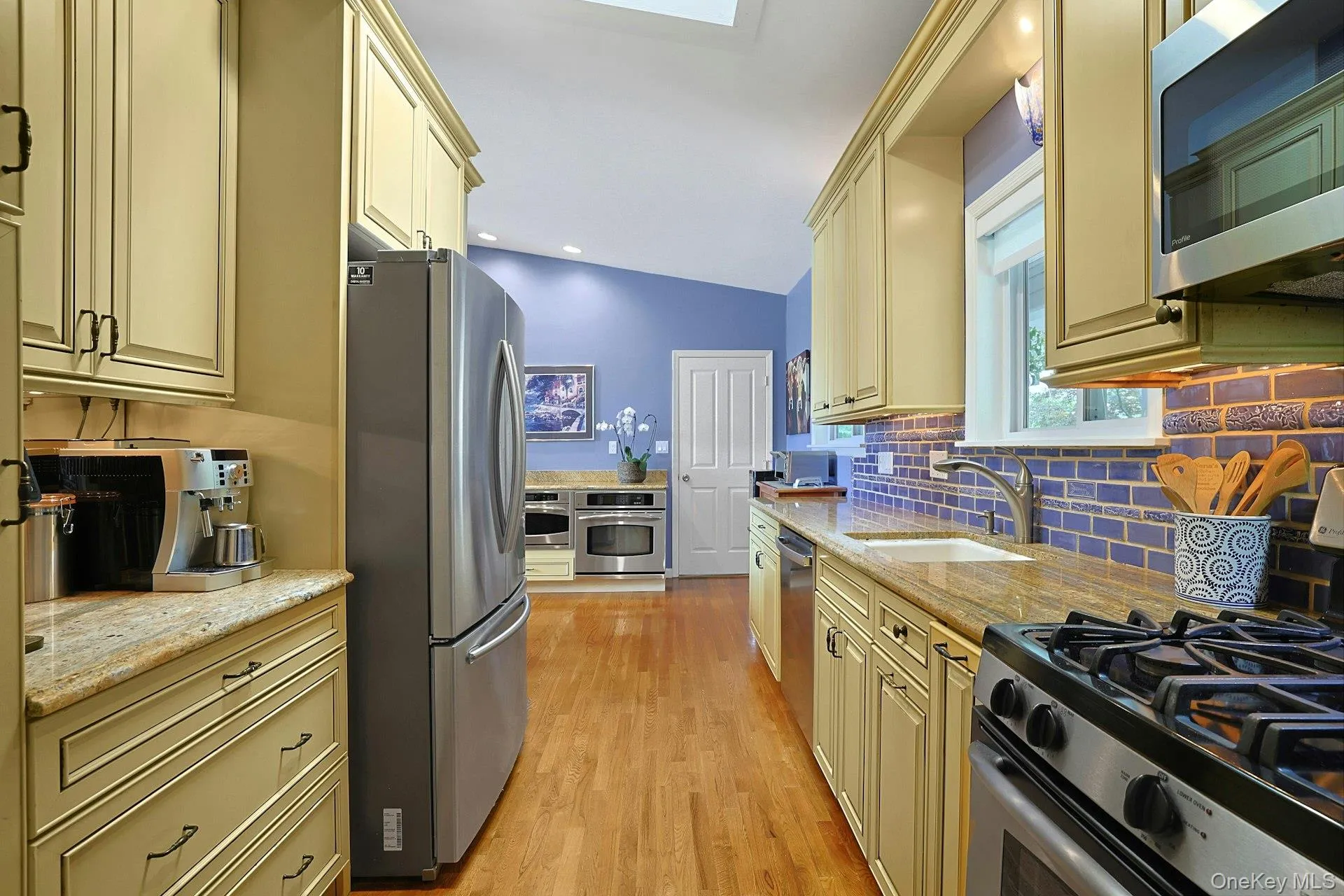 A beautifully appointed chef's kitchen featuring stainless steel appliances: 4 ovens including a range with upper and lower oven, a Trivection oven, a GE Profile oven, and a view of the garden from the kitchen window A beautifully appointed chef's kitchen featuring stainless steel appliances: 4 ovens including a range with upper and lower oven, a Trivection oven, a GE Profile oven, and a view of the garden from the kitchen window