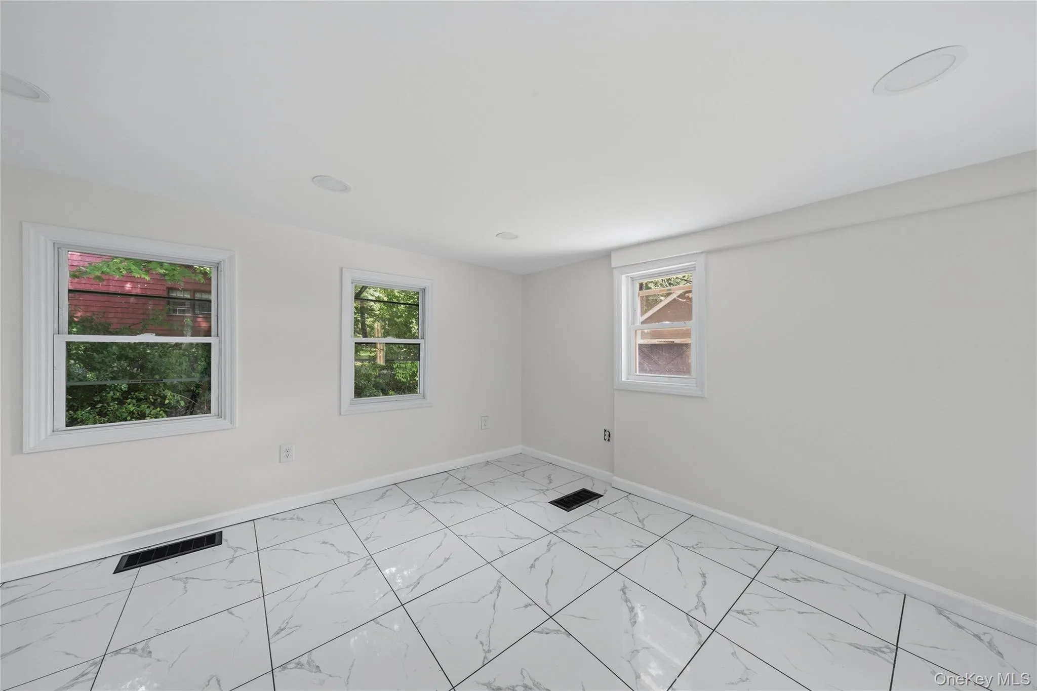 Spacious room with white walls, recessed ceiling lighting, and three windows providing abundant natural light Spacious room with white walls, recessed ceiling lighting, and three windows providing abundant natural light