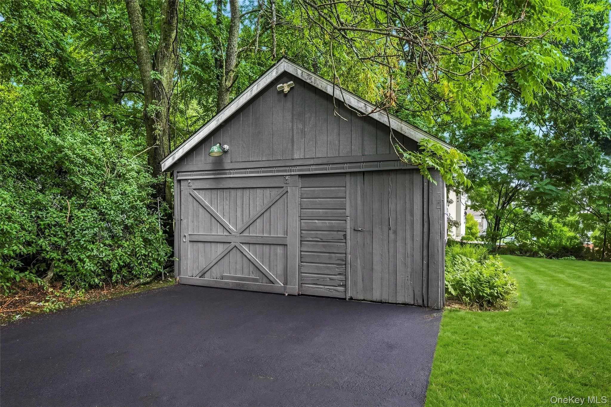 Detached shed featuring board-and-batten siding, a gable roof, and sliding barn doors Detached shed featuring board-and-batten siding, a gable roof, and sliding barn doors